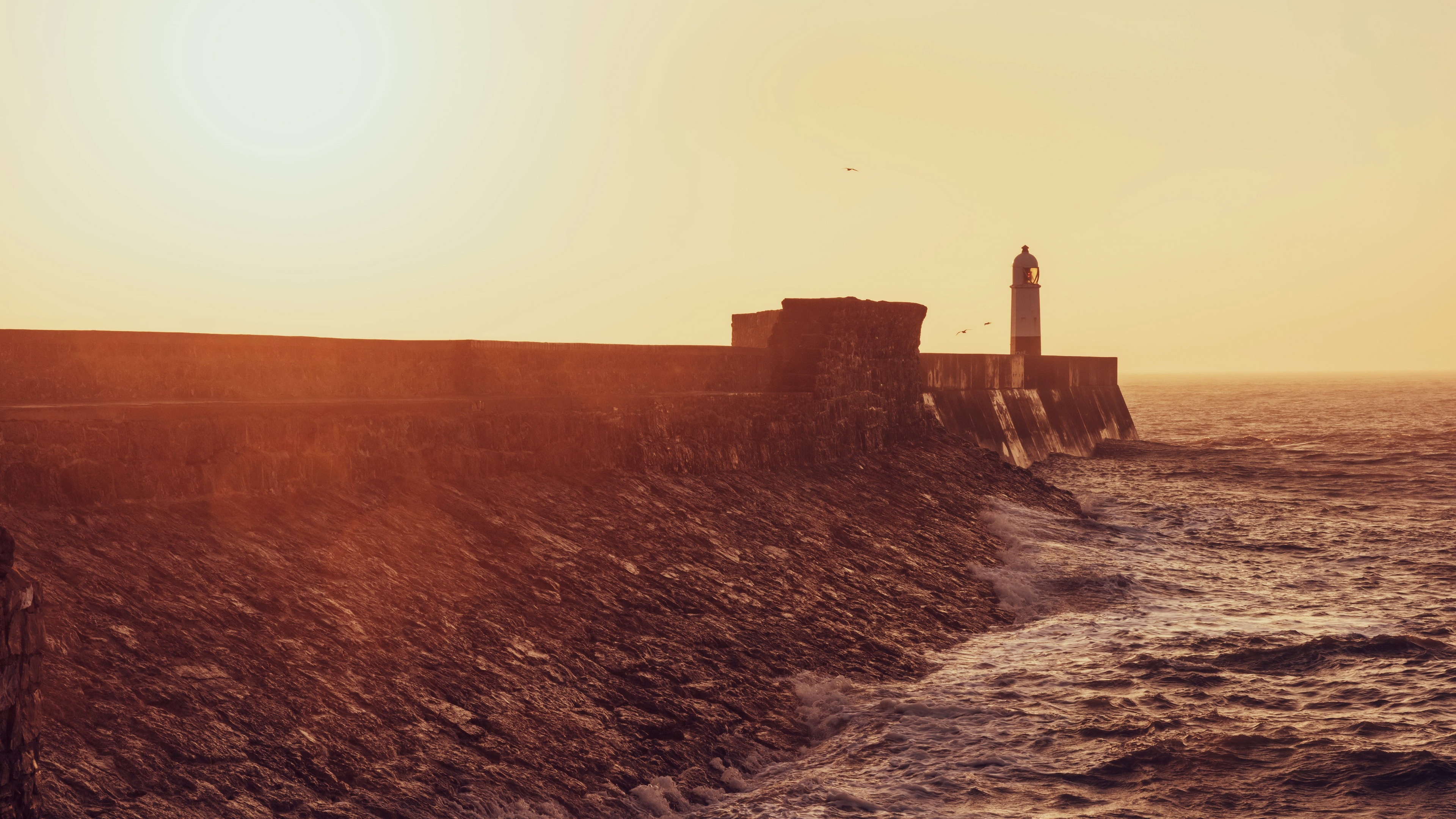 4K lighthouse on a rocky coast at sunset HD Wallpaper