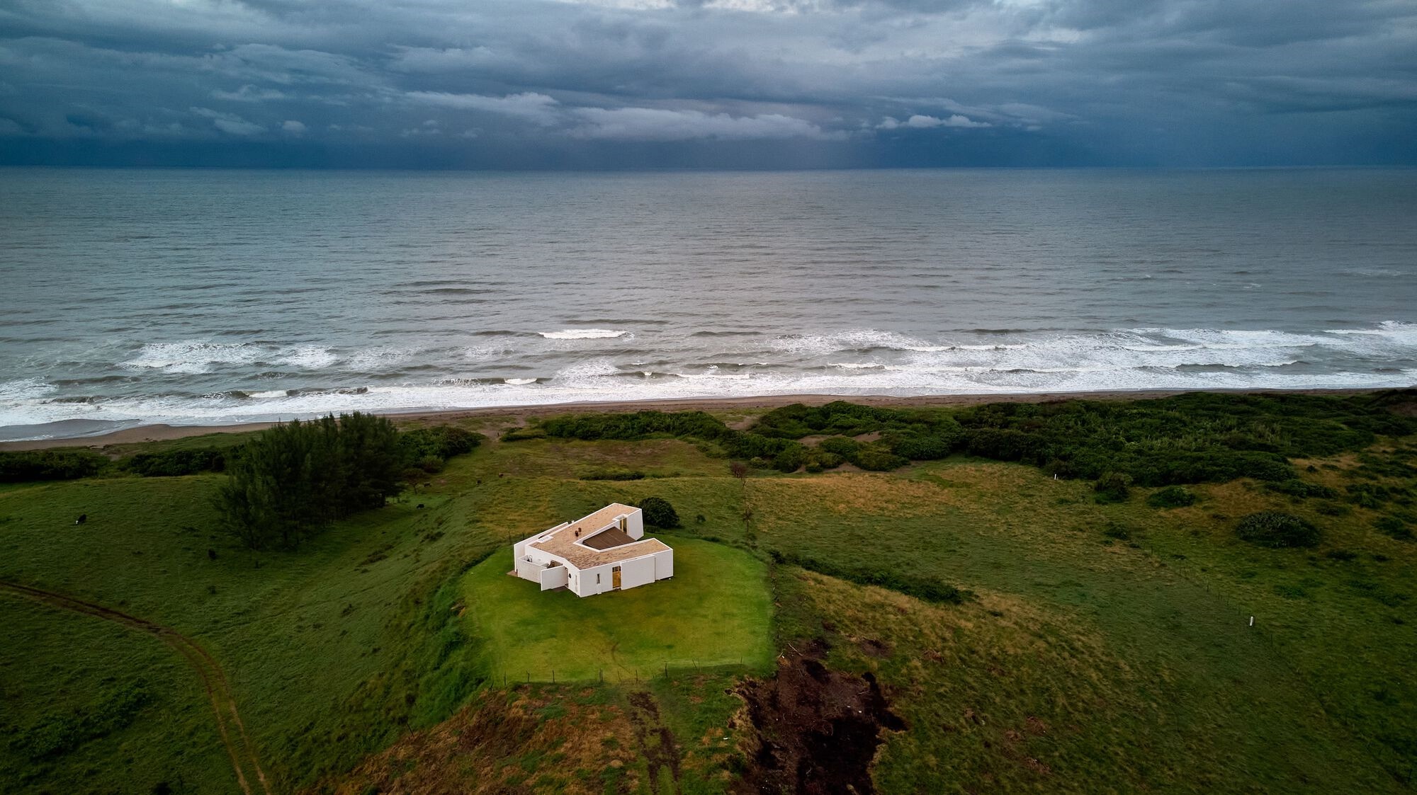 Modern house on a grassy hill overlooking the sea HD Wallpaper
