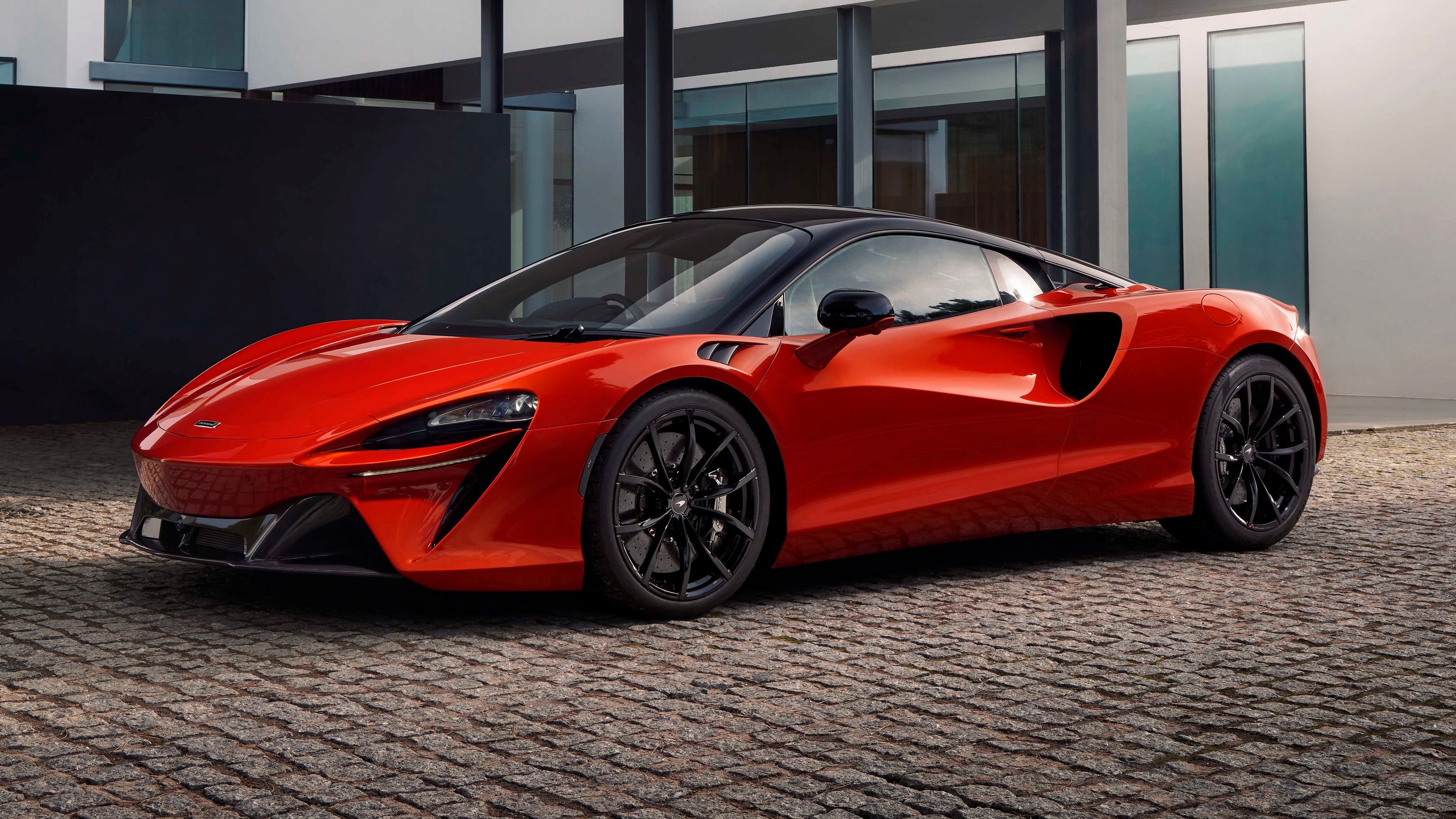Red McLaren sports car parked on cobblestone HD Wallpaper