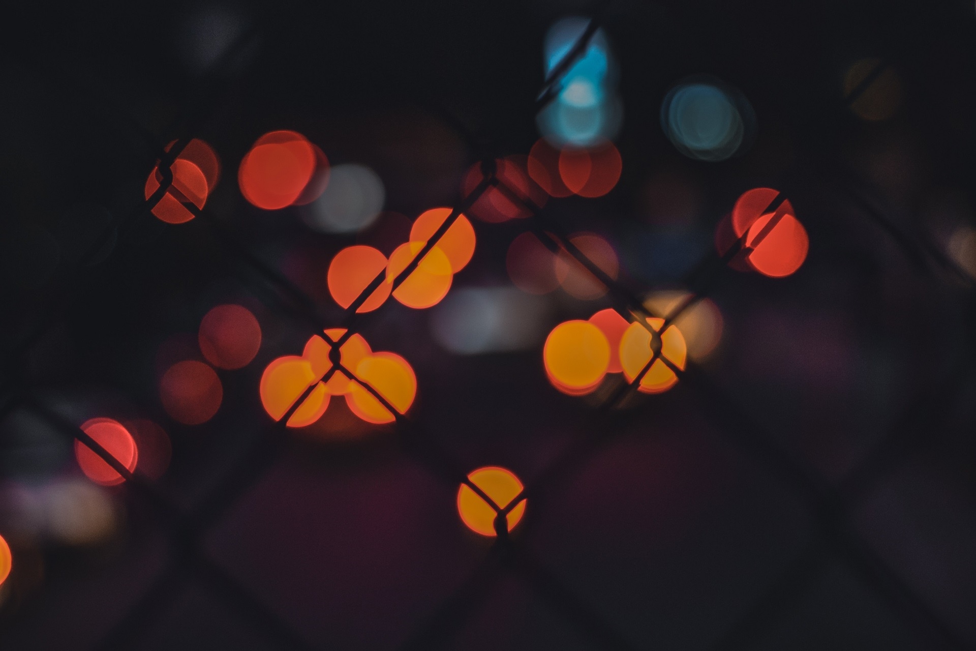 Bokeh lights behind a wire fence at night HD Wallpaper