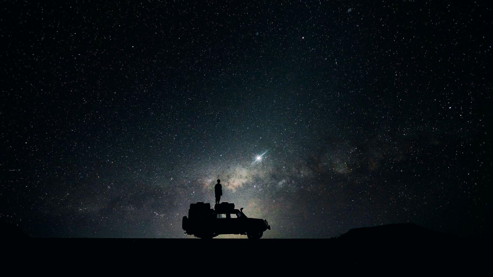 Silhouette of a person on a car under the night sky HD Wallpaper