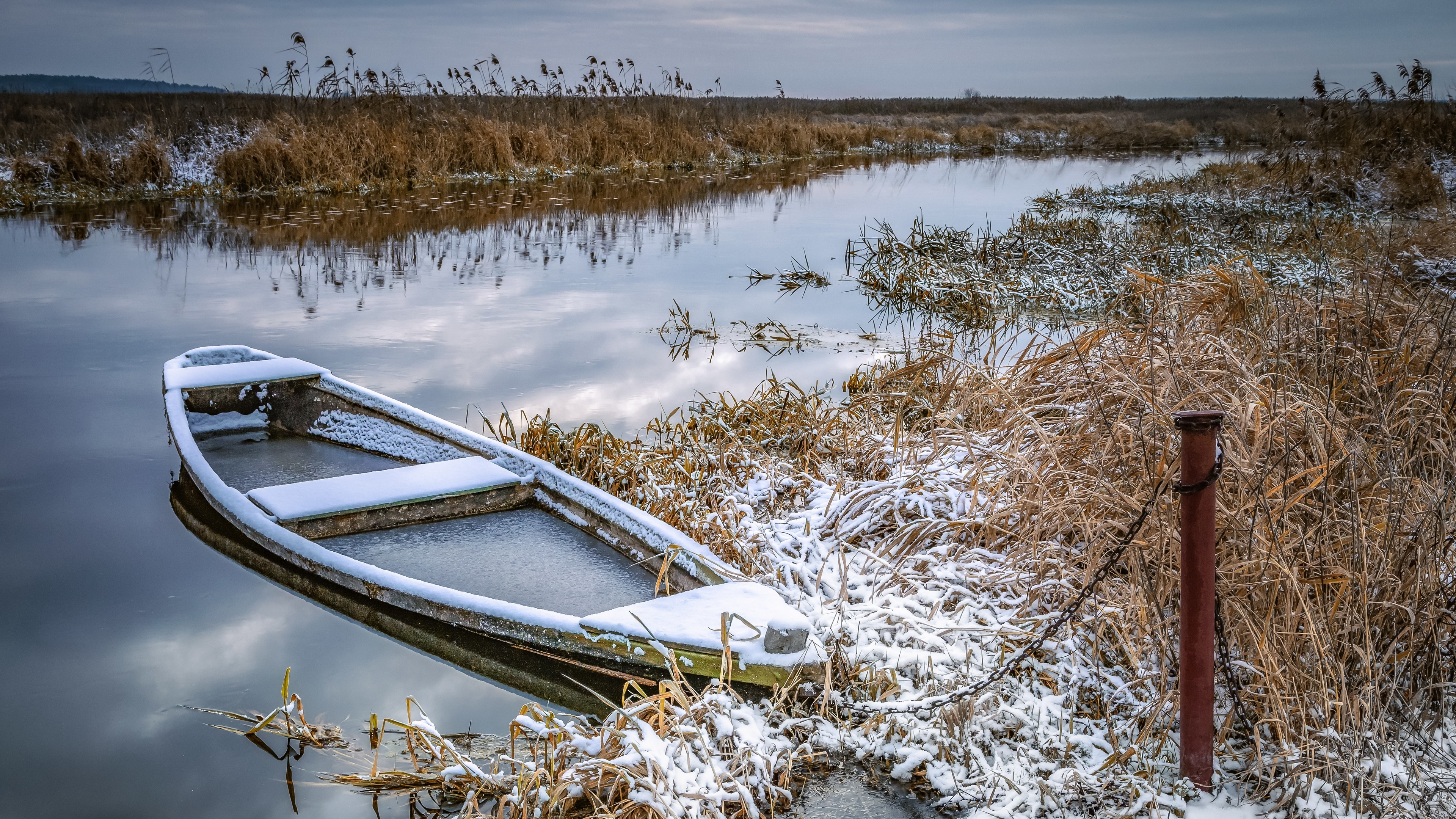 Boat covered in snow on a calm winter lake HD Wallpaper
