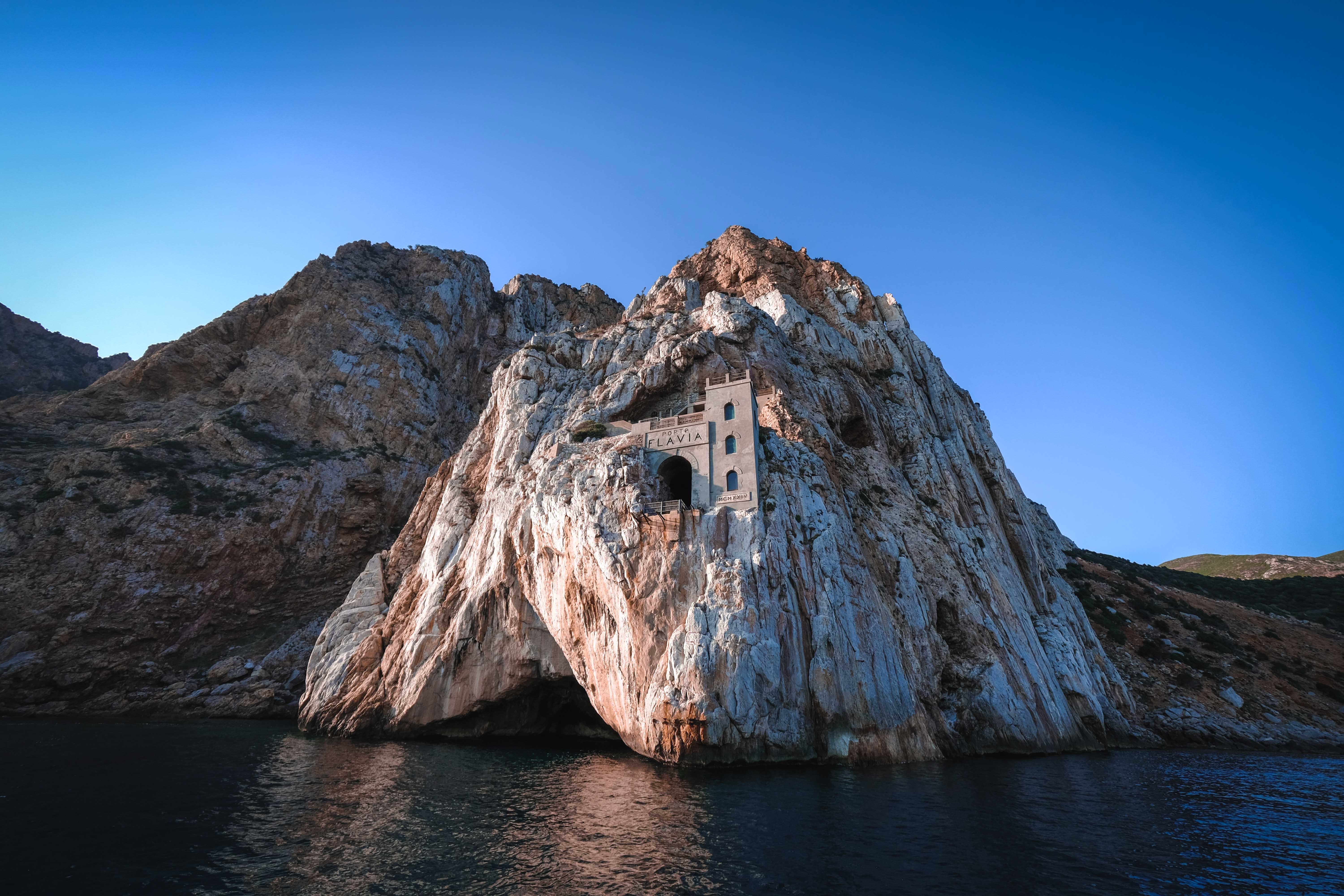 Flavia building carved into a rocky cliff face HD Wallpaper