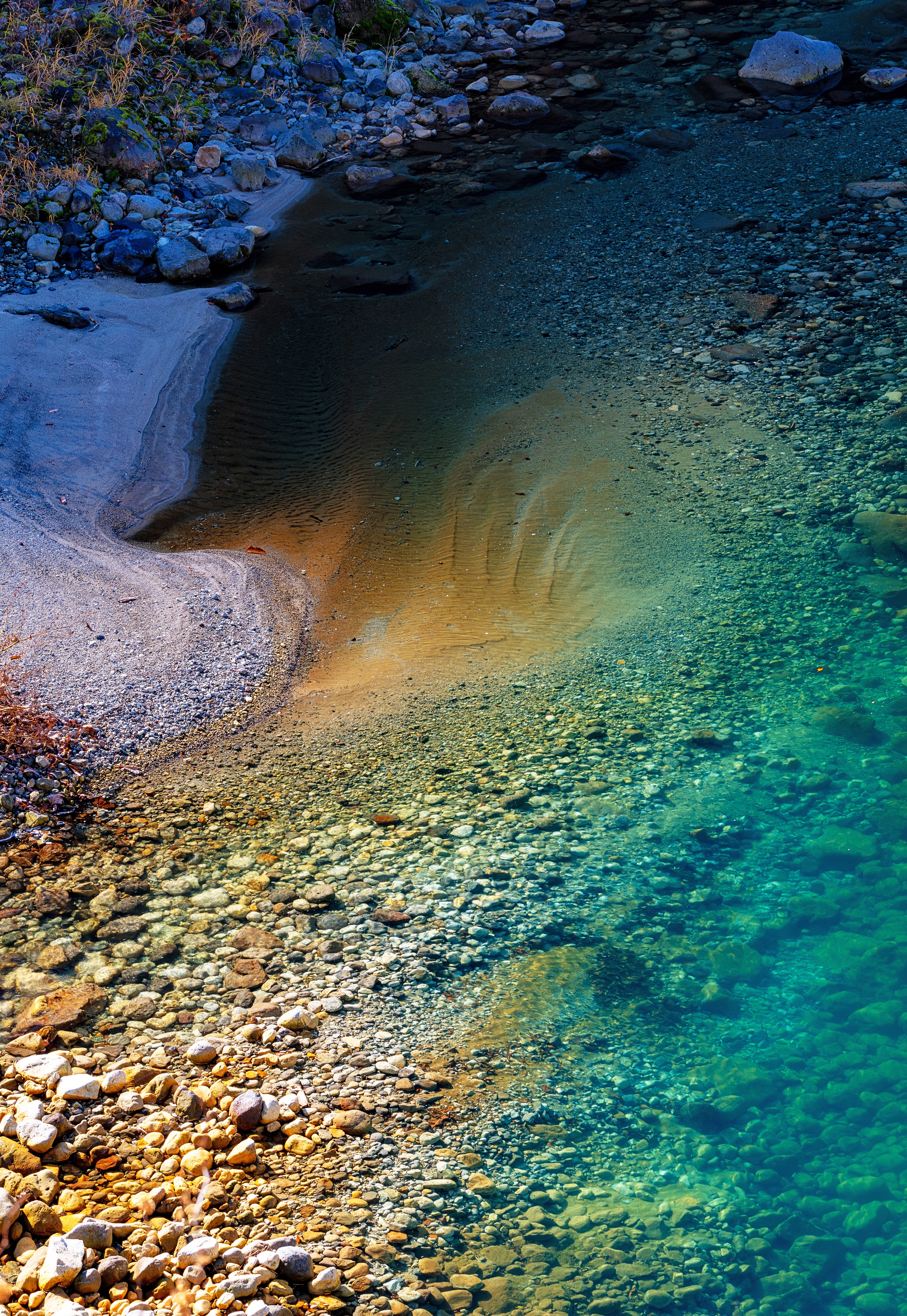 Clear river water flowing over colorful pebbles and sand HD Phone Wallpaper