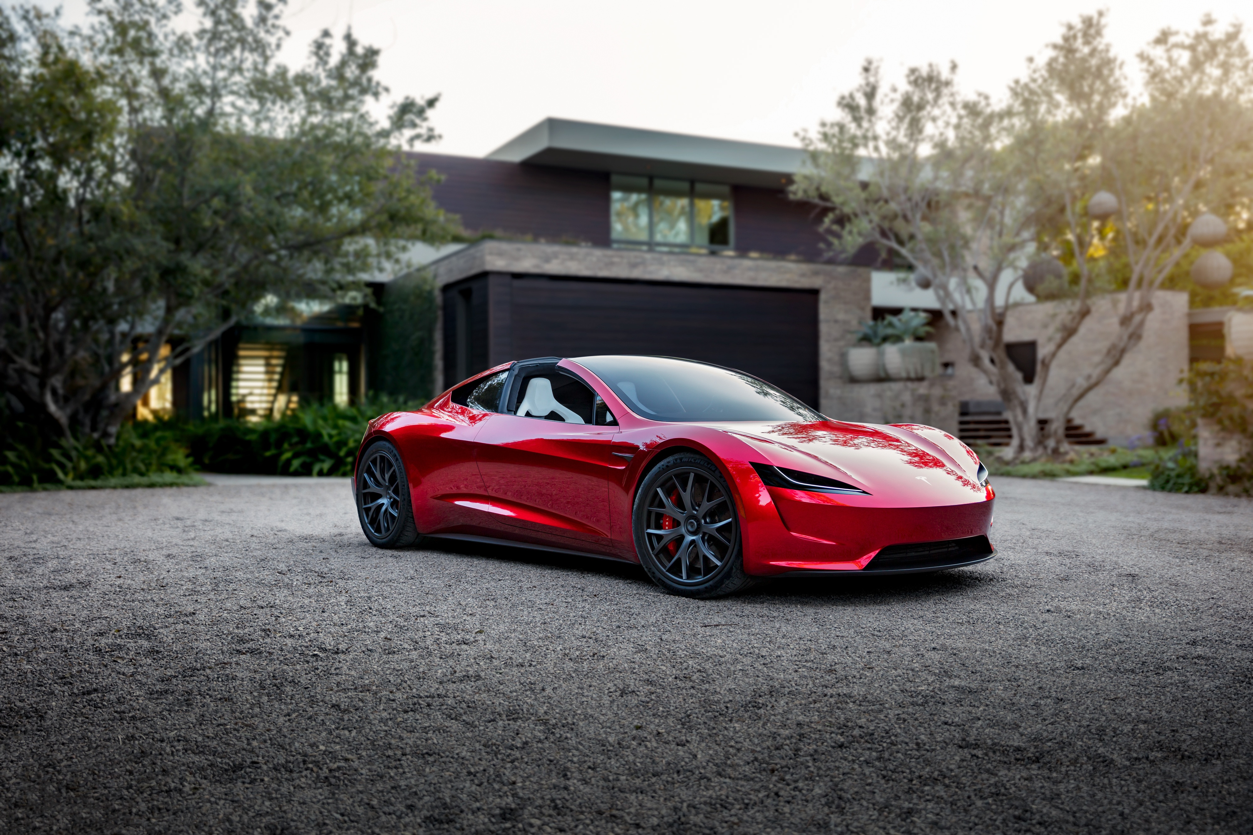 Red Tesla Roadster parked in front of a modern house HD Wallpaper
