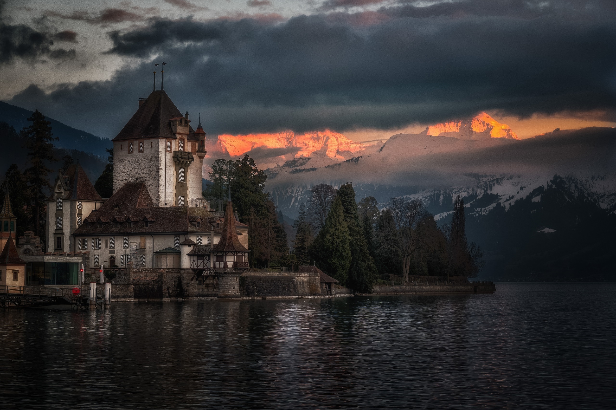 Castle Oberhofen on a lake with mountains at sunset HD Wallpaper