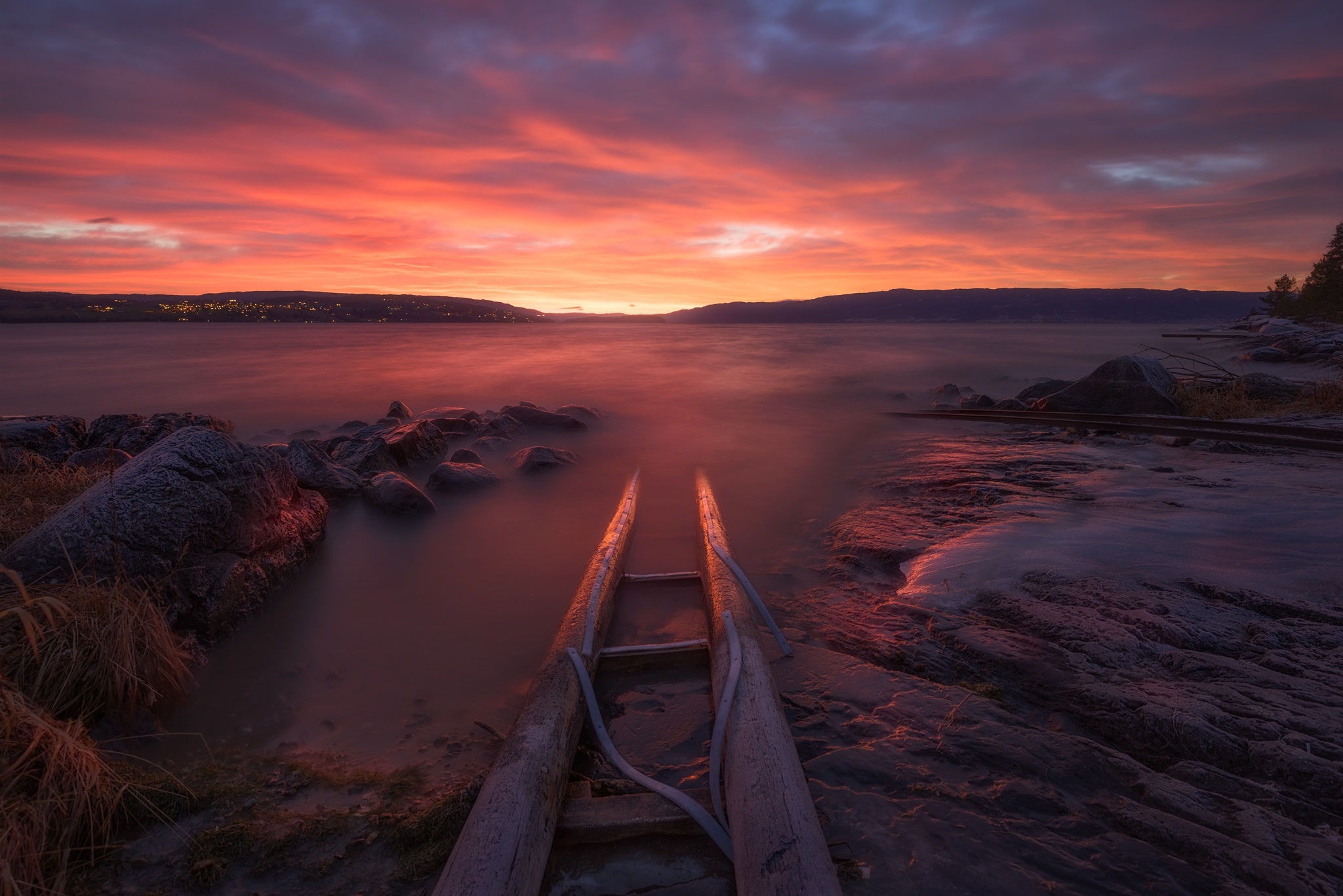 Sunset over a calm lake with a wooden boat ramp HD Wallpaper