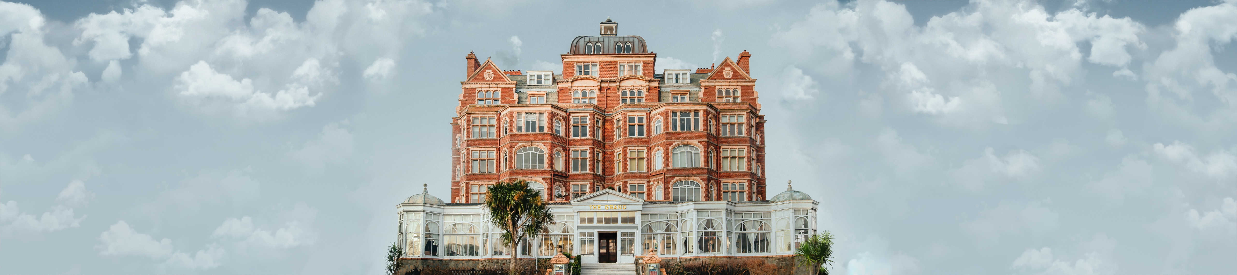 4K ultrawide view of a grand brick building against a cloudy sky HD Wallpaper