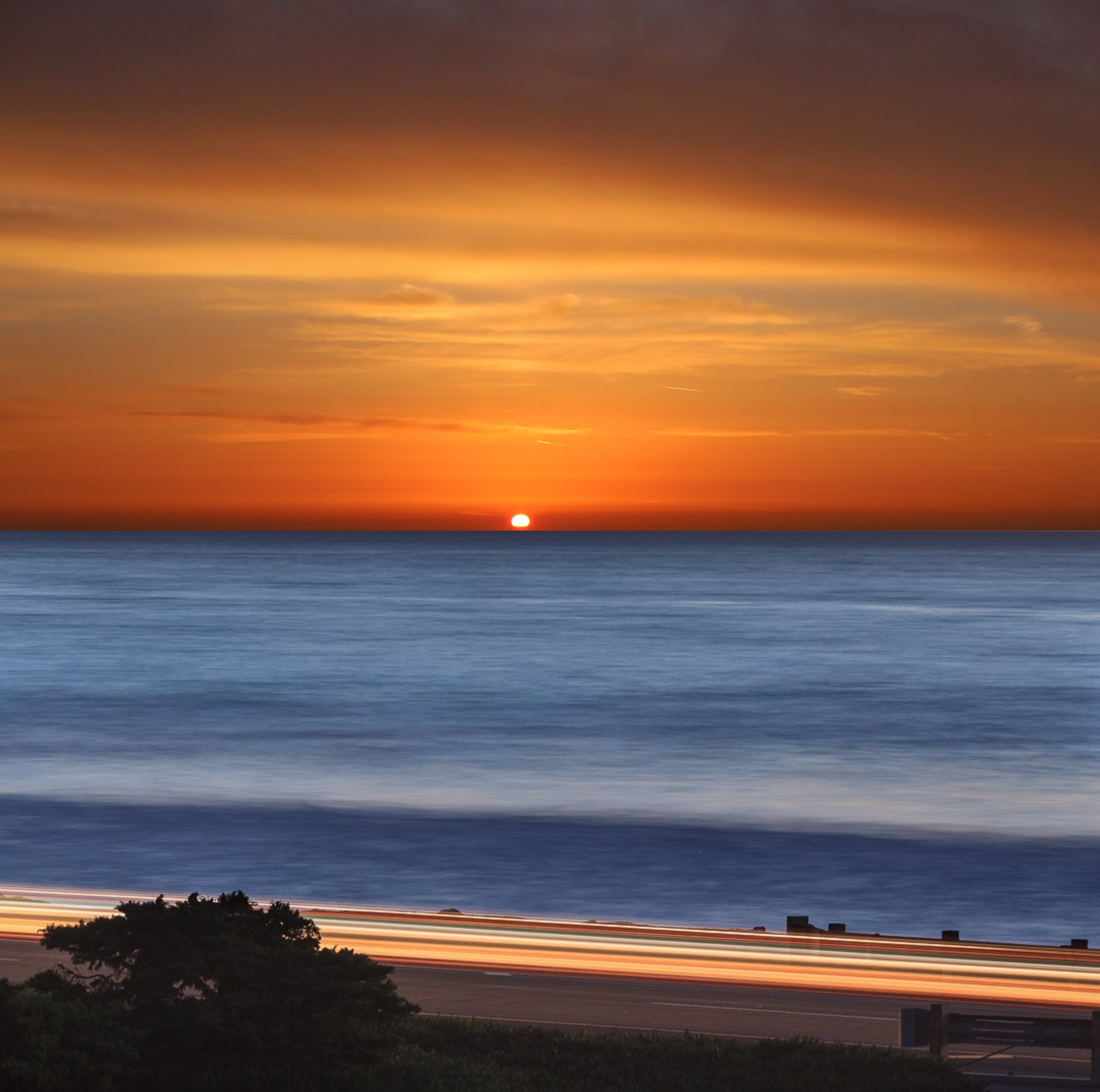 Sunset over the ocean with light trails on a road HD Wallpaper