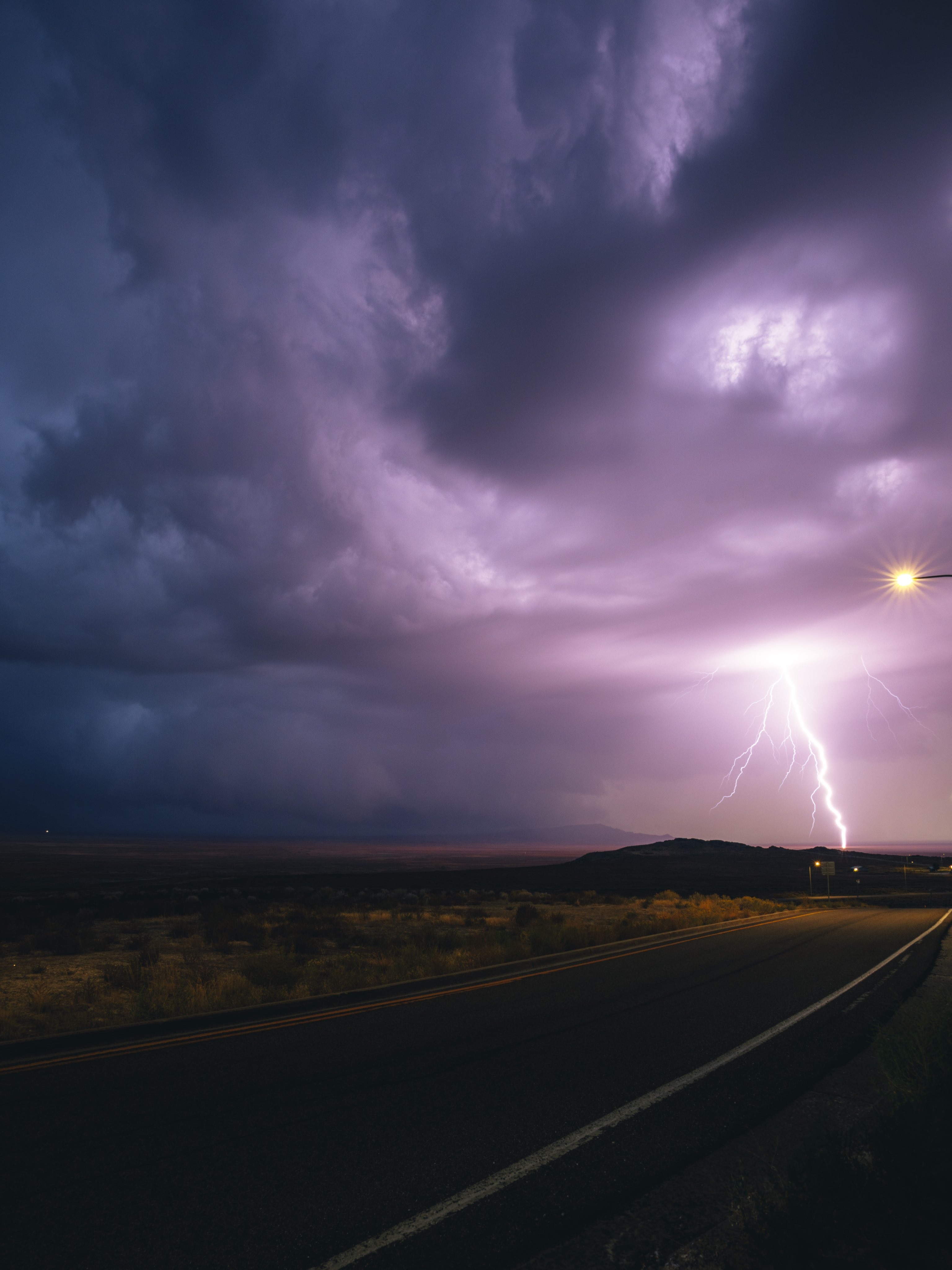Lightning strikes over a desert road at night HD Phone Wallpaper