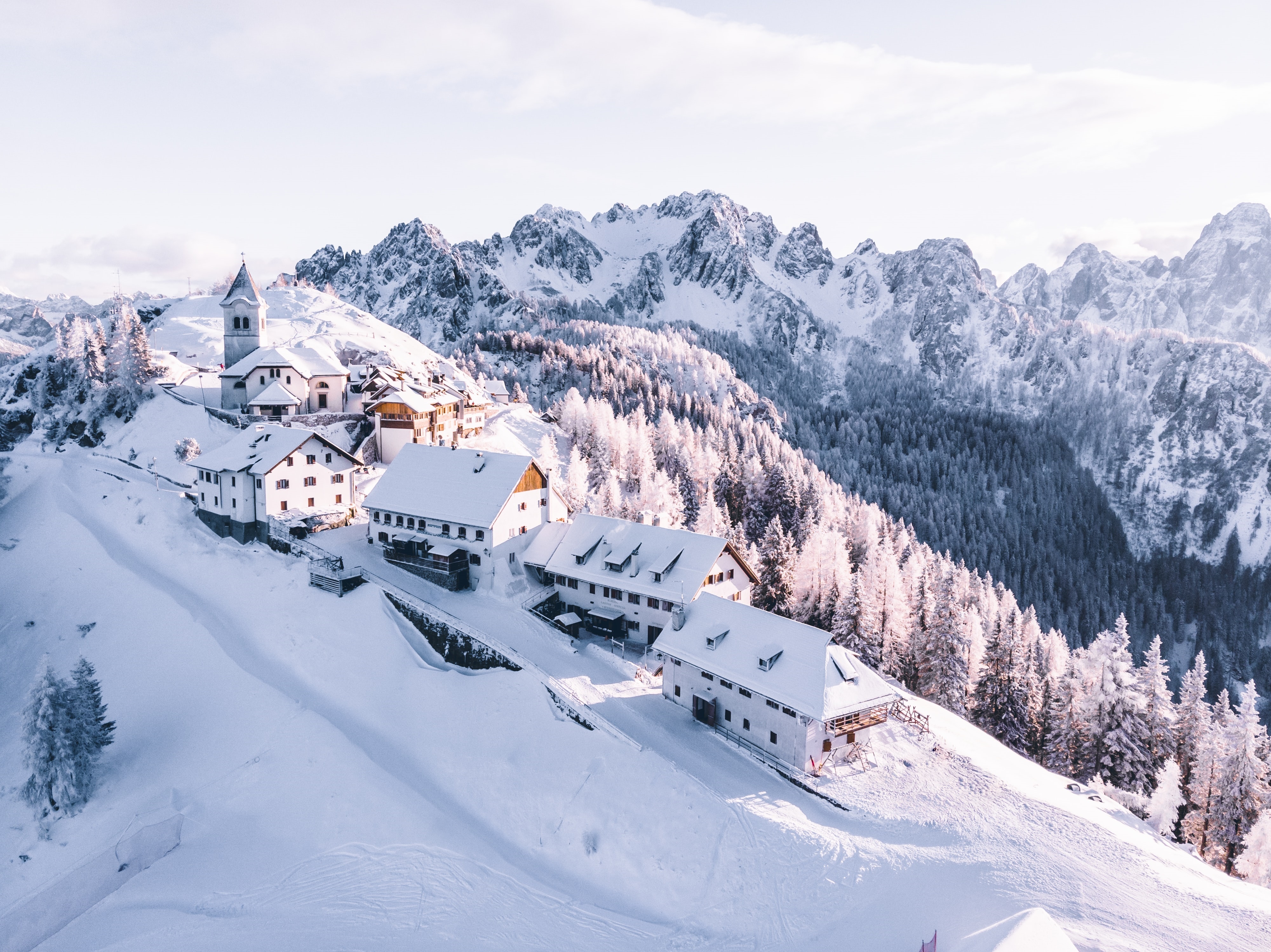 4K aerial view of a snowy mountain village in the Alps HD Wallpaper