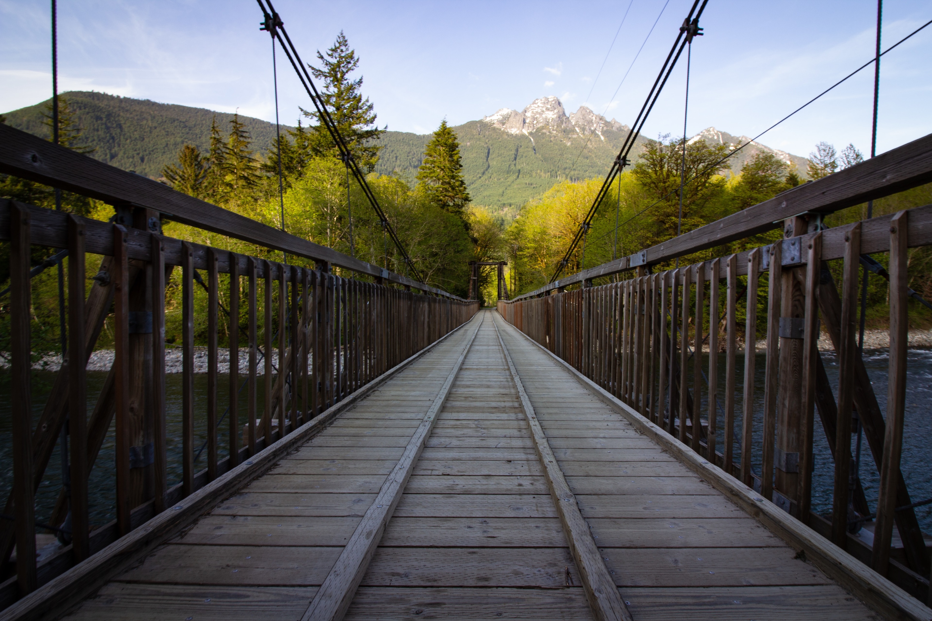 Wooden suspension bridge over a river with mountains HD Wallpaper