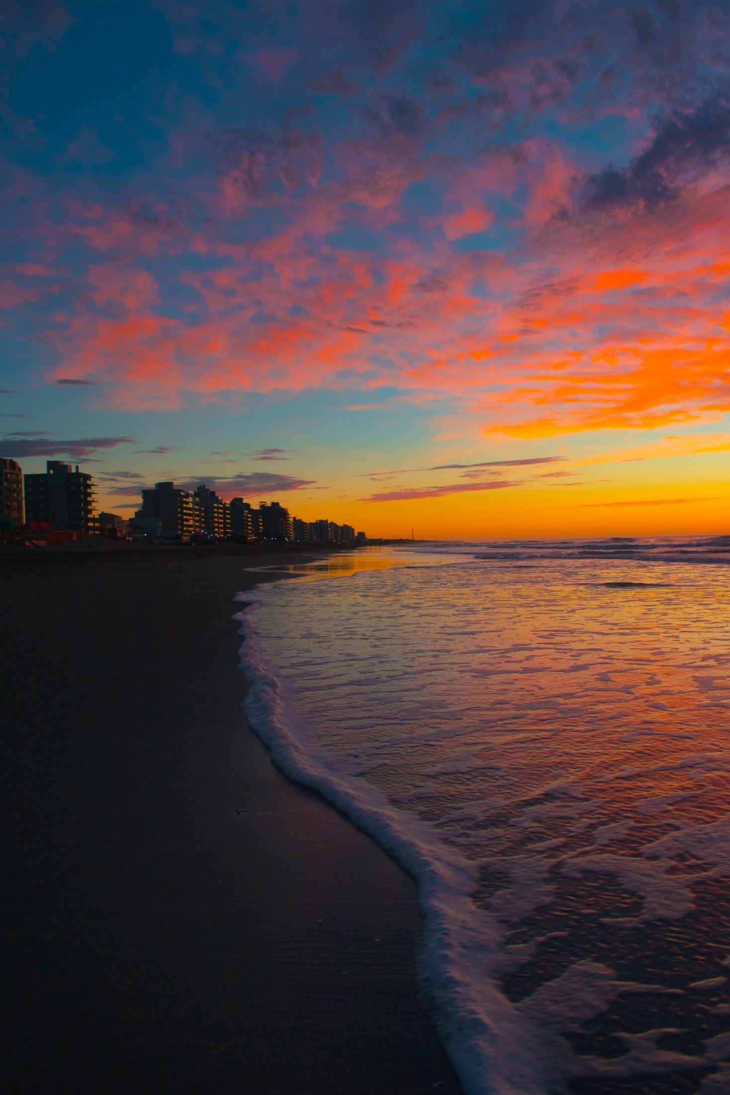 Beach apartments at sunset with colorful sky and ocean waves HD Phone Wallpaper