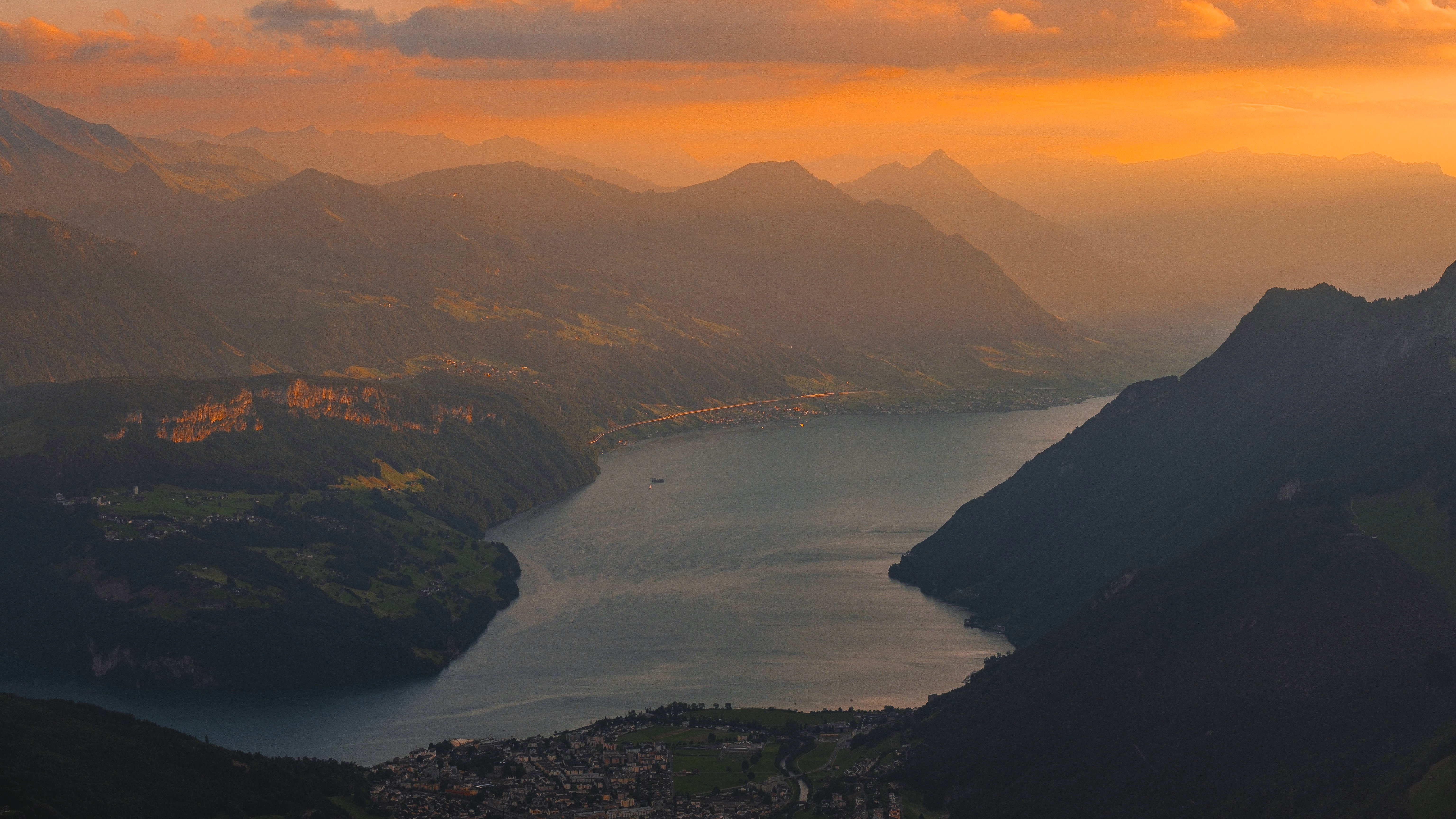 Sunset over a mountain lake with a town below HD Wallpaper