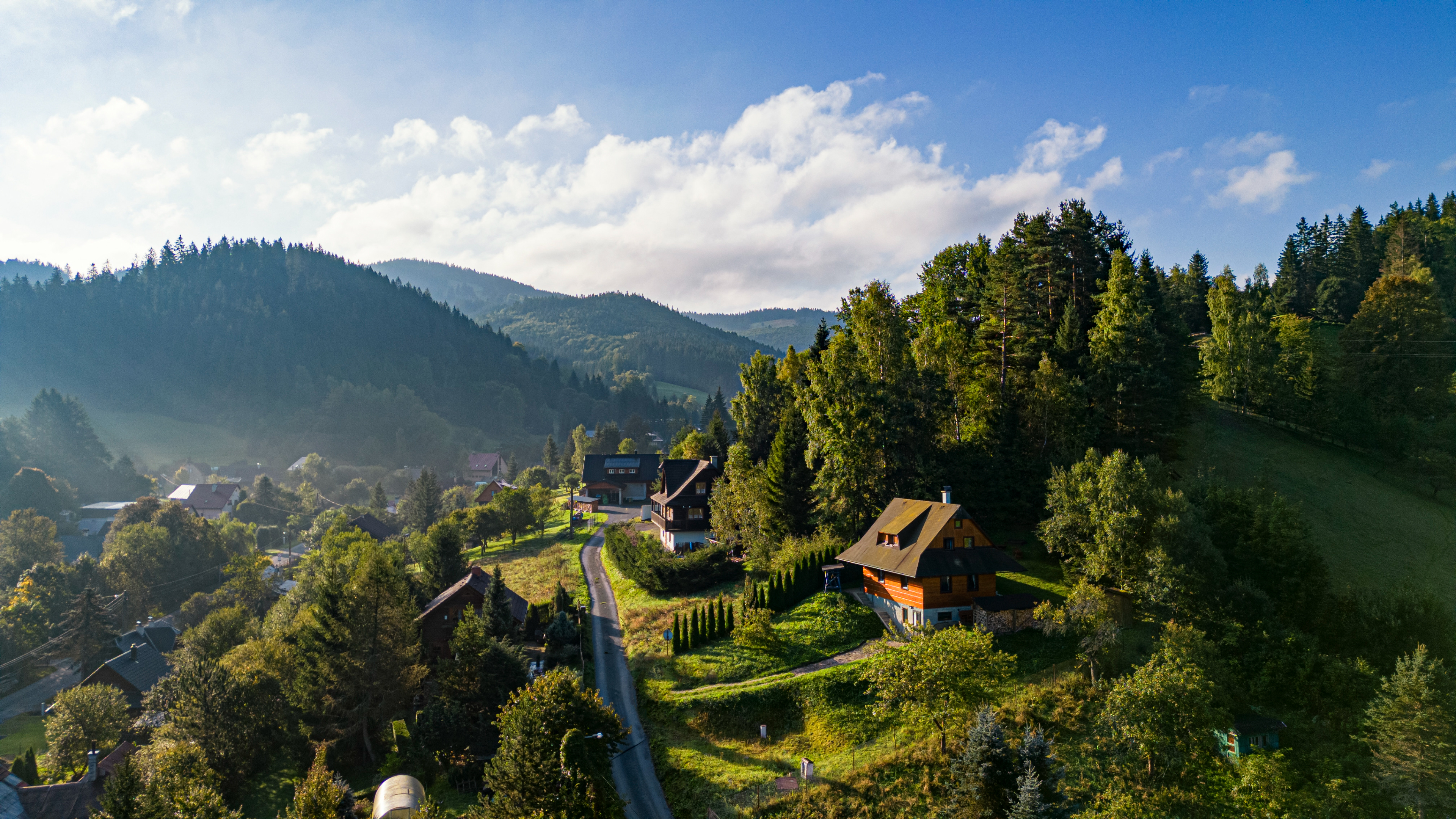 Aerial view of a village nestled in a mountainous landscape with trees HD Wallpaper
