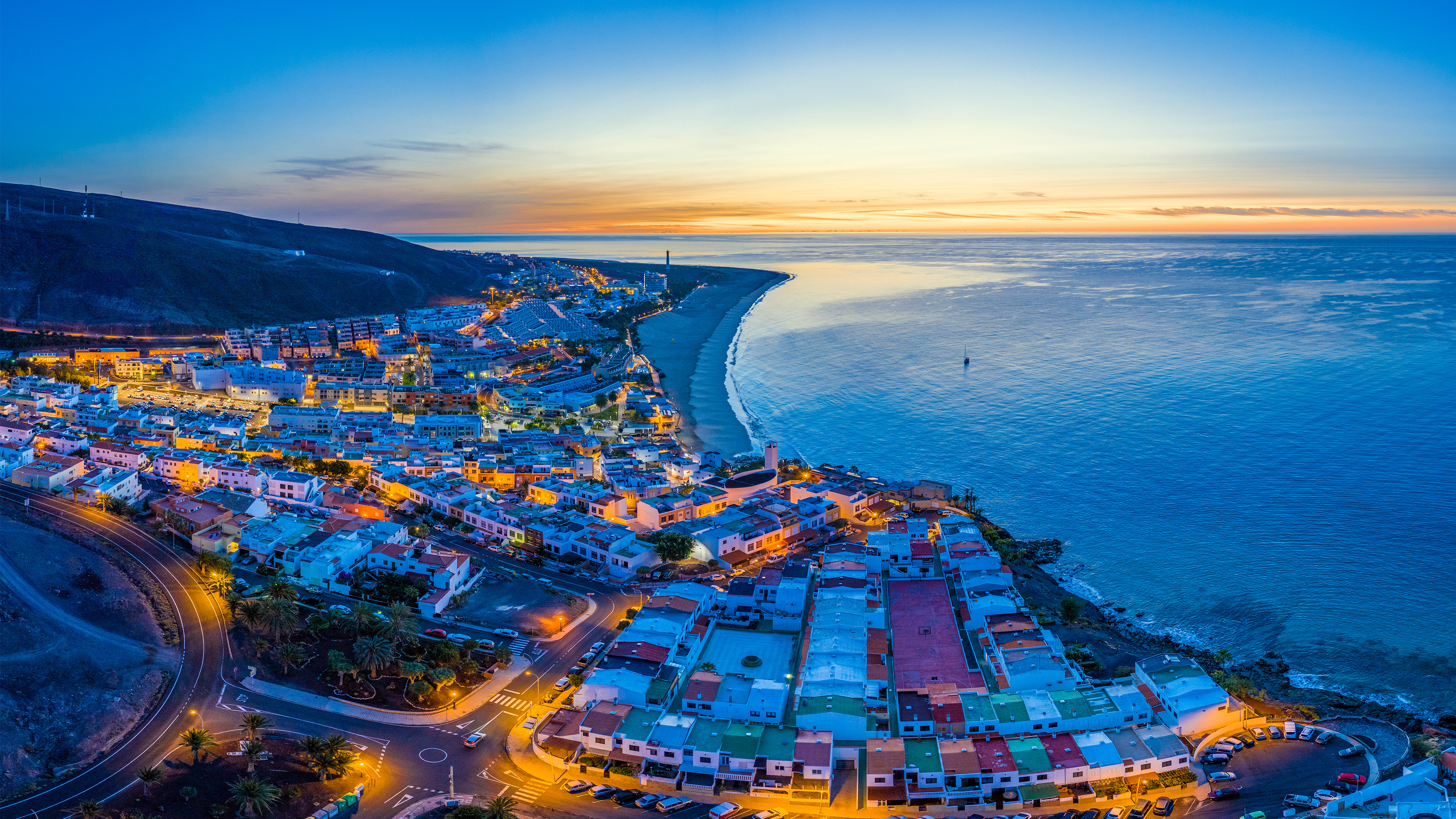 Coastal town at sunset with ocean and mountains HD Wallpaper