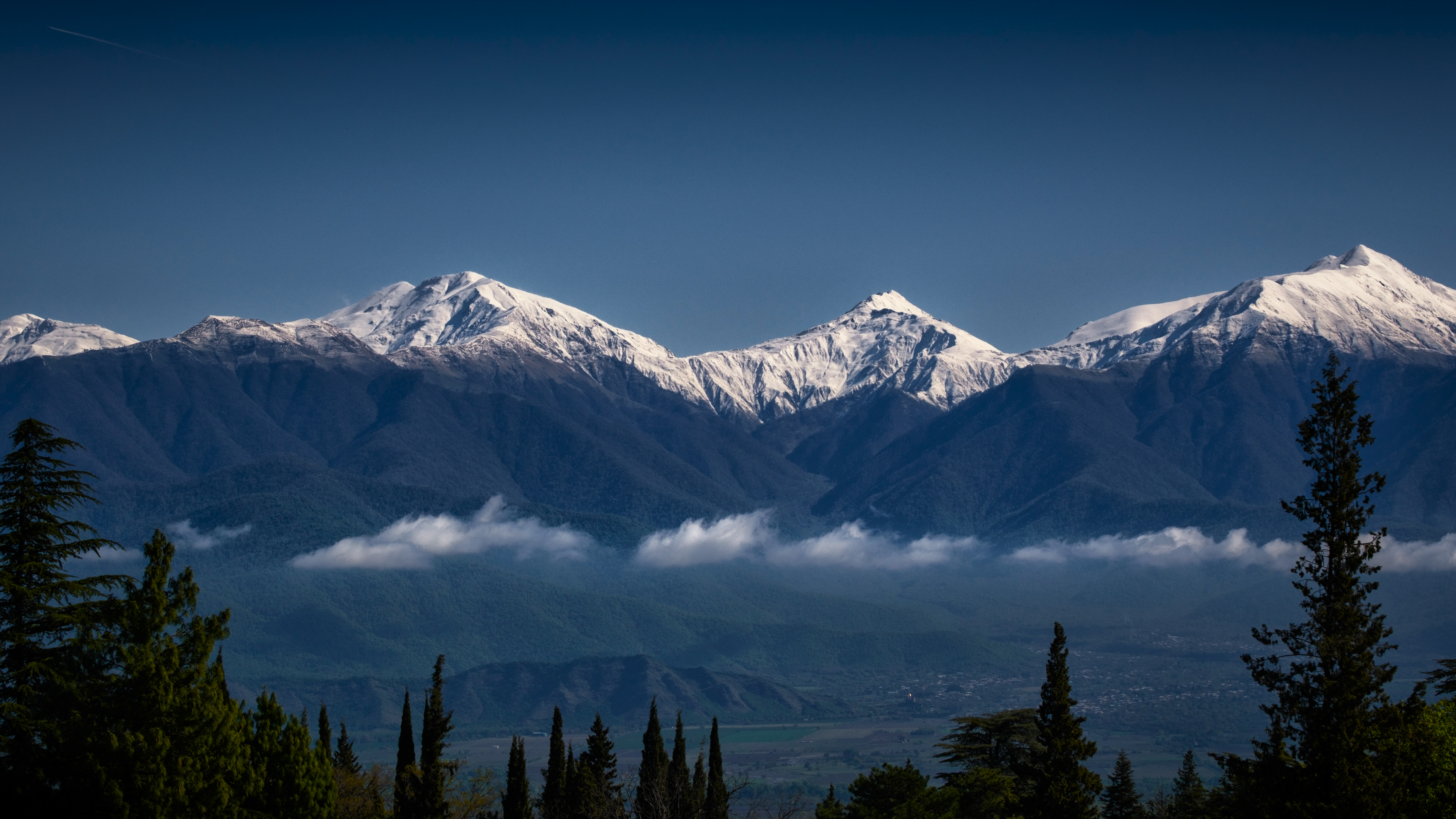 Snow-covered mountains under a clear blue sky HD Wallpaper
