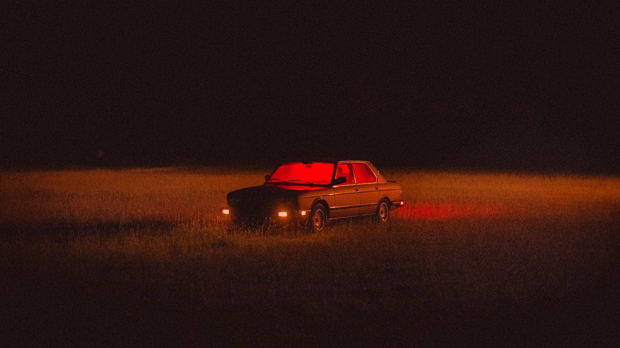 Car with red lights in a dark field at night HD Wallpaper