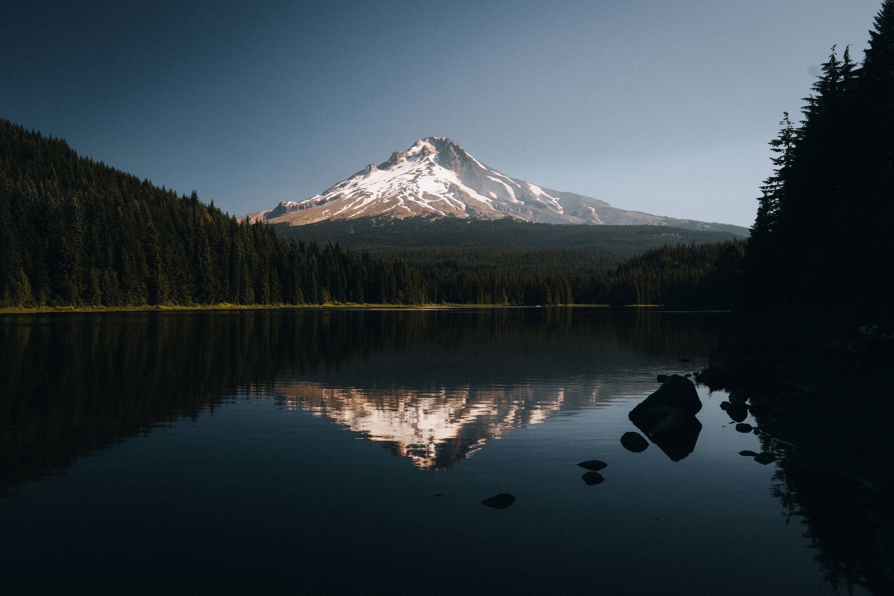 Mount Hood reflected in a calm lake with surrounding forest HD Wallpaper