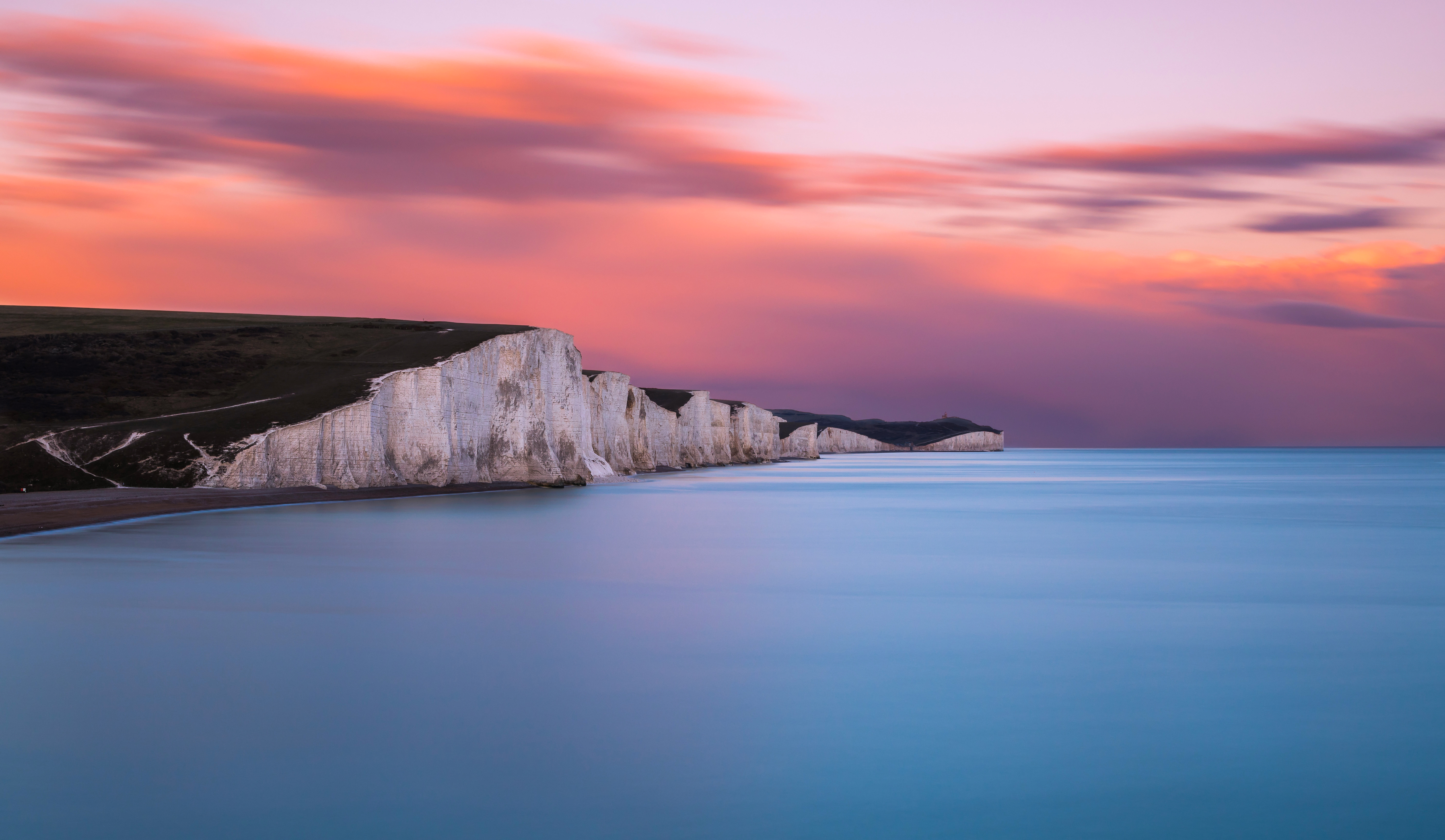 White cliffs and ocean at sunset with pink clouds HD Wallpaper