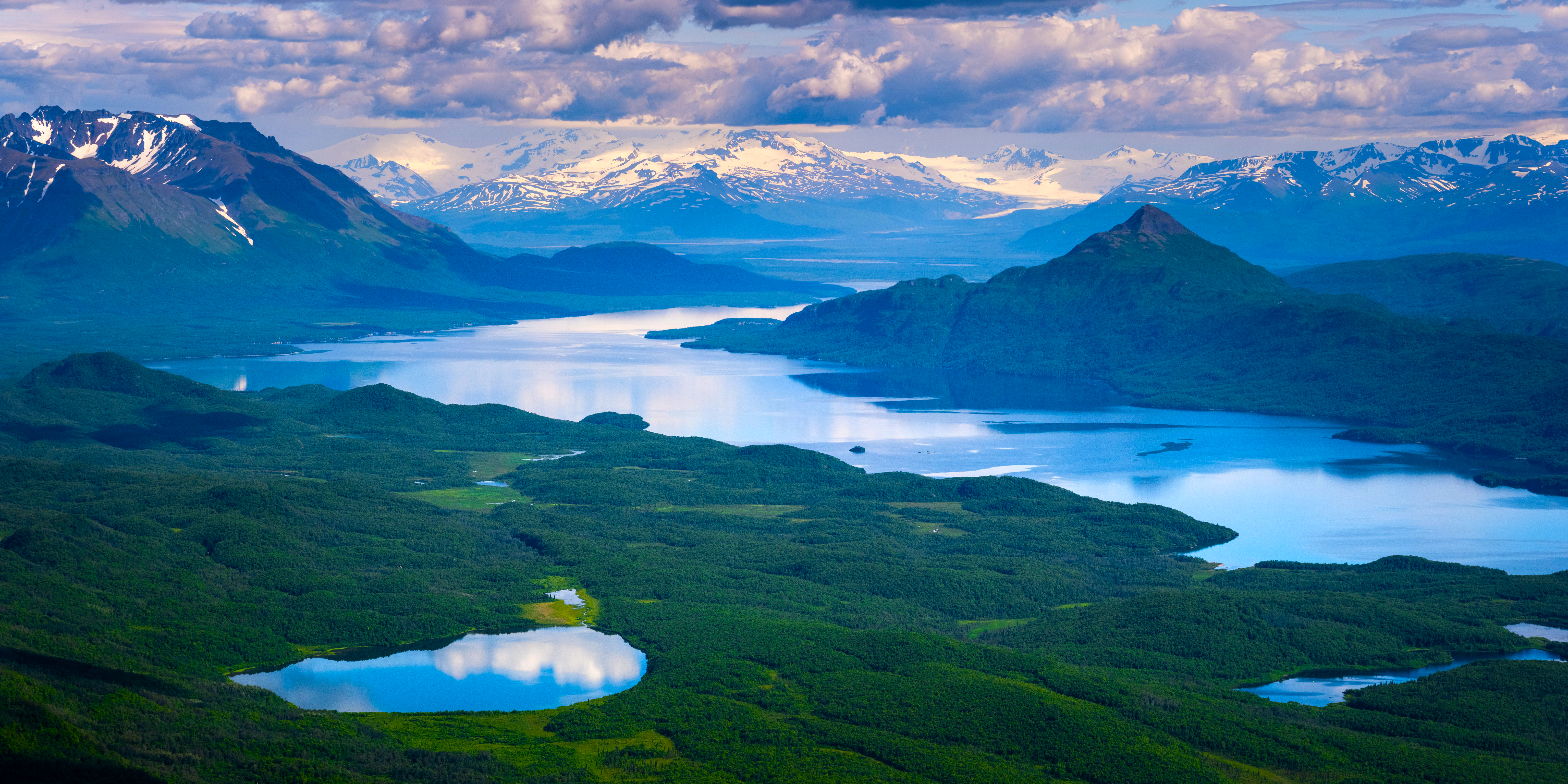 Aerial view of a vast lake and snow-capped mountains HD Wallpaper