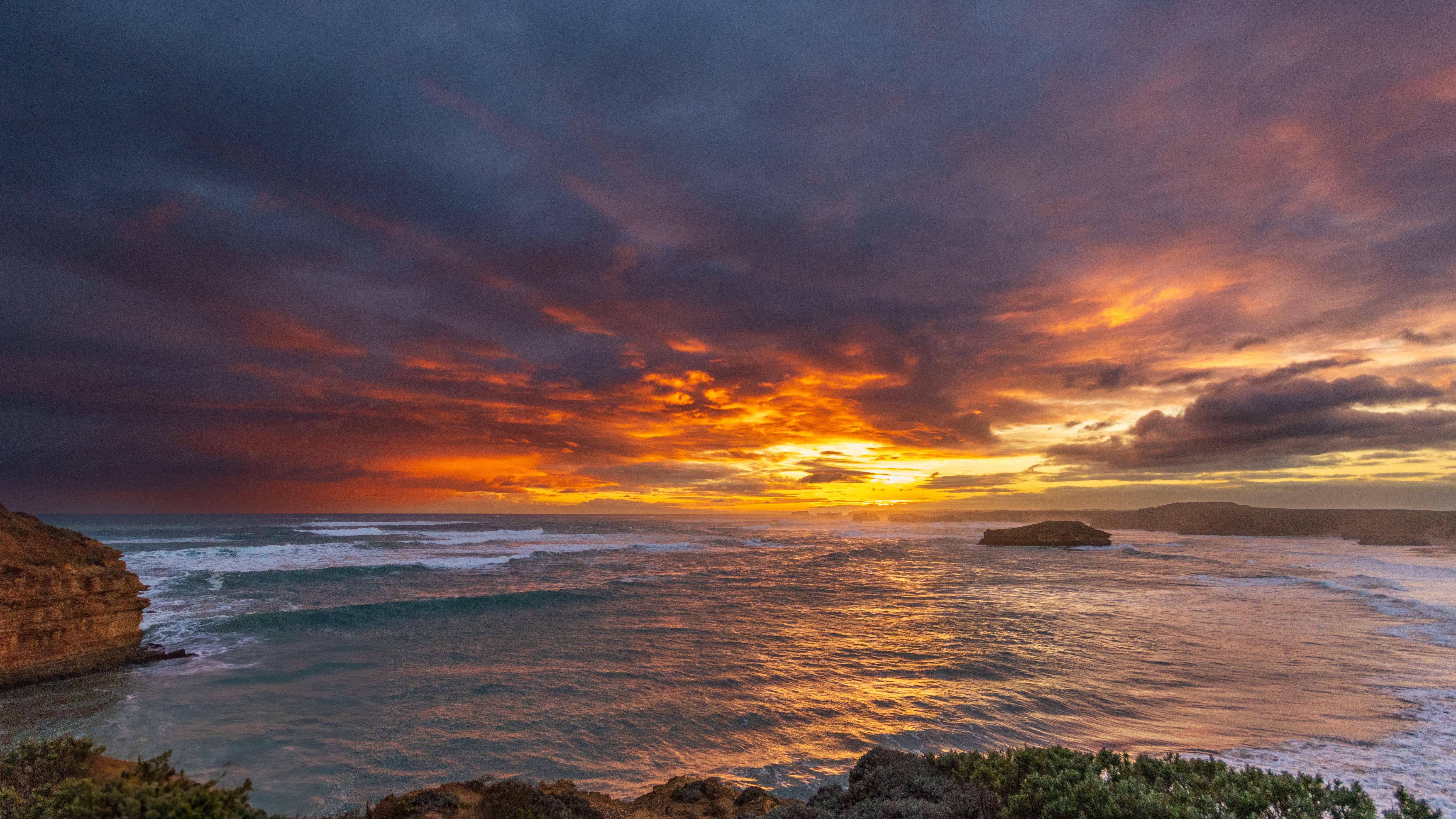 Sunset over the ocean with dramatic clouds and waves HD Wallpaper