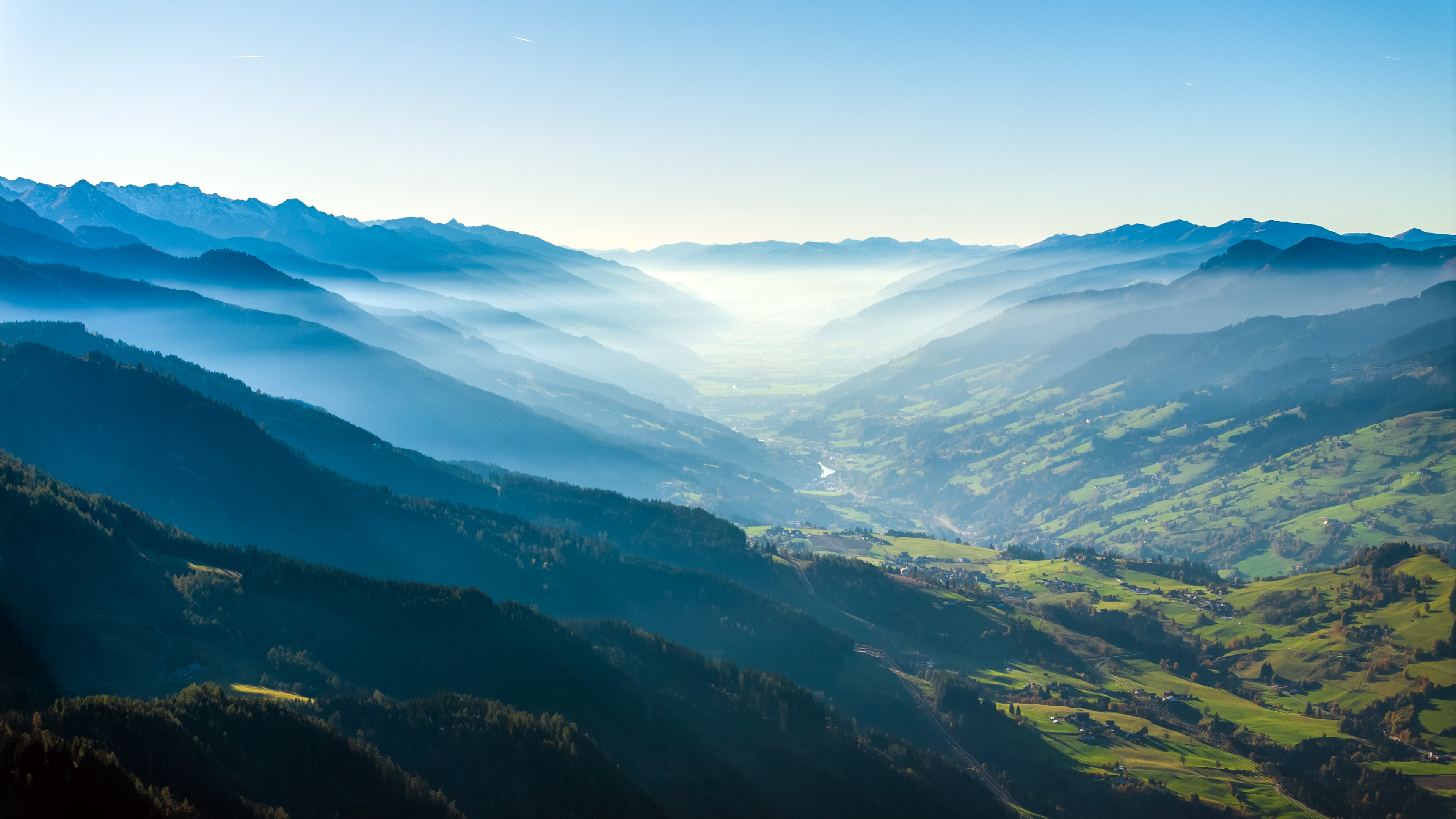Misty valley with mountains and a village HD Wallpaper