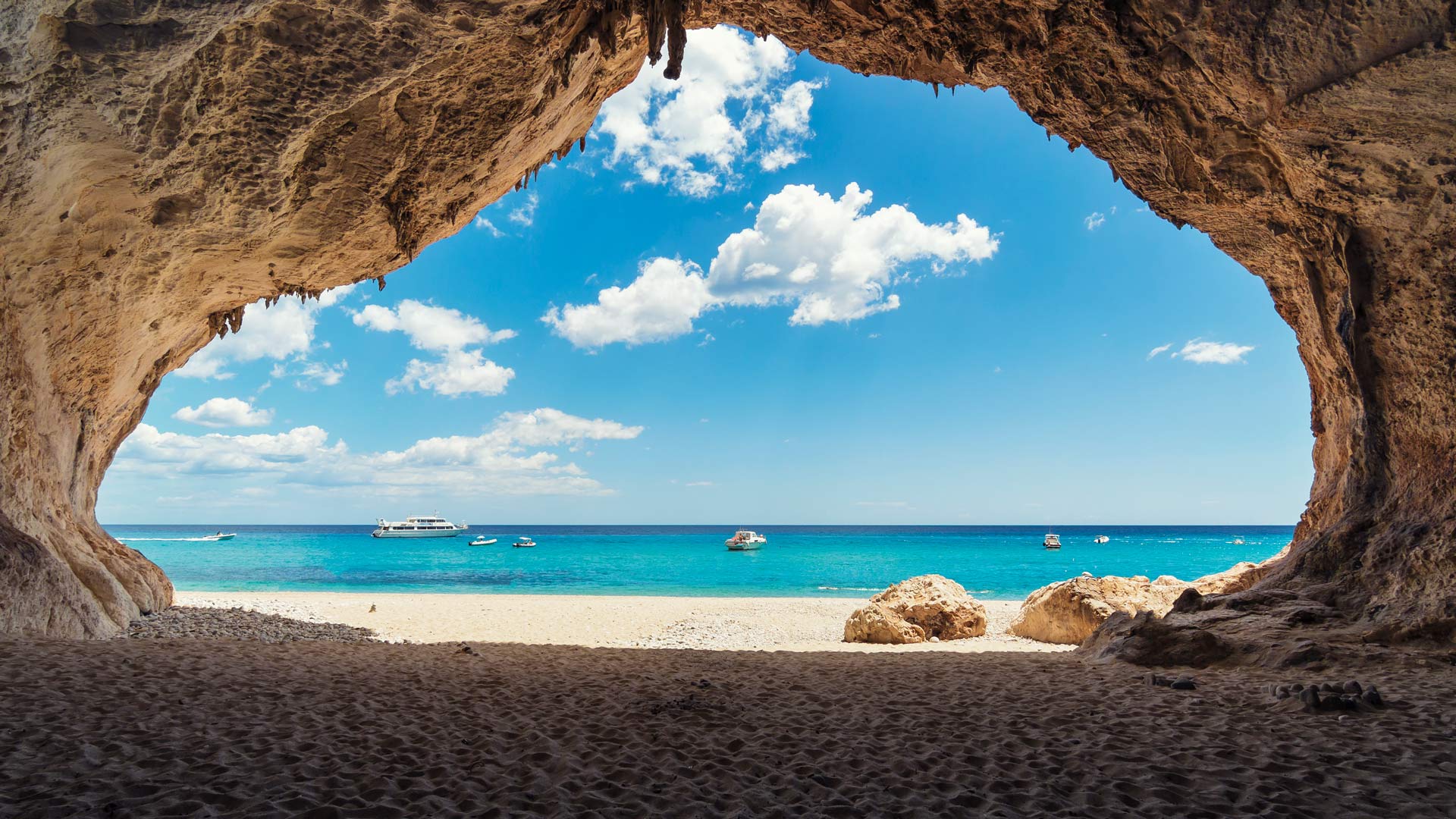 Boats on a turquoise sea viewed from a cave entrance HD Wallpaper