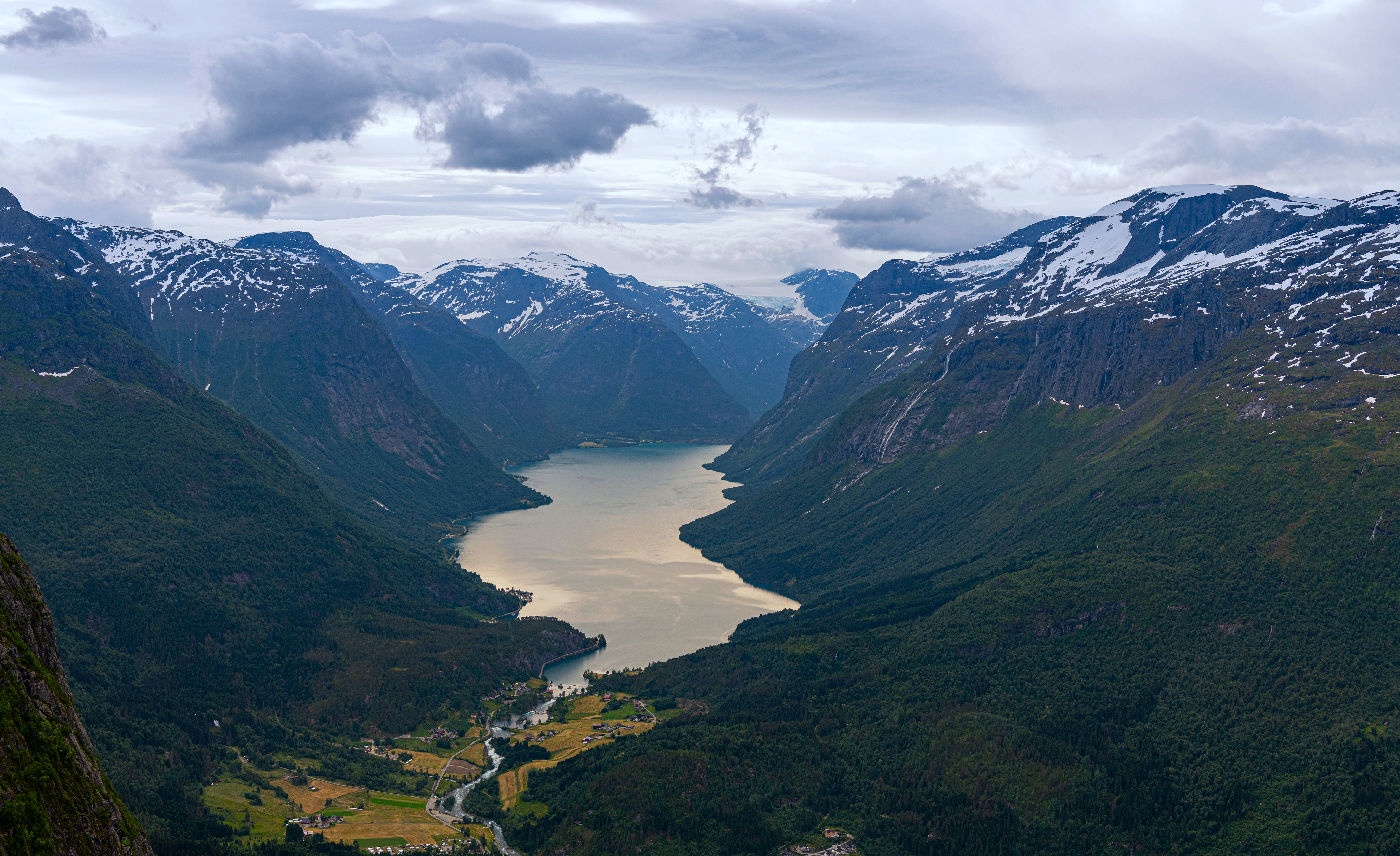 A wide valley with a lake and snow-capped mountains HD Wallpaper