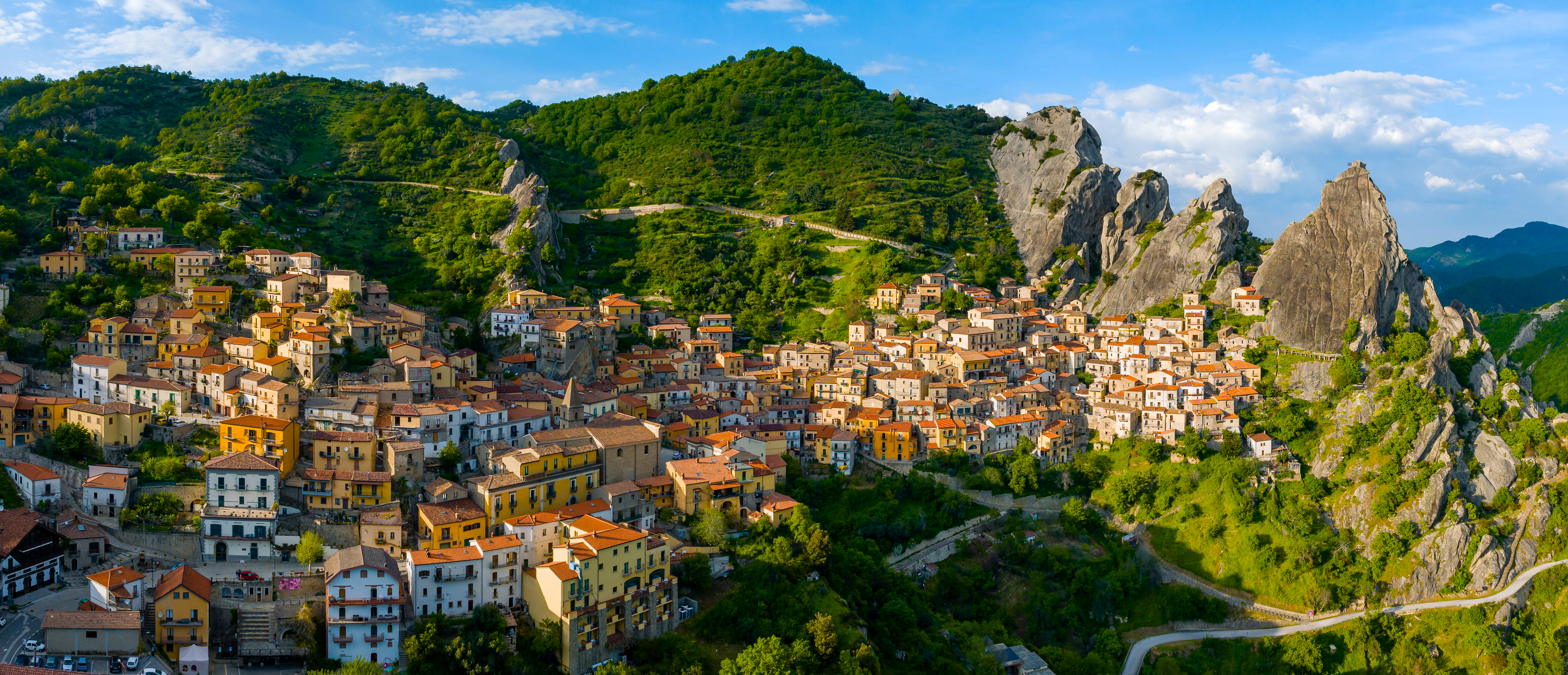 Village nestled in a green mountain landscape HD Wallpaper