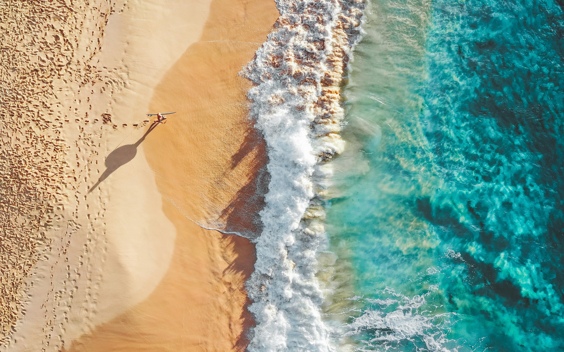 Aerial view of a beach with waves and footprints HD Wallpaper