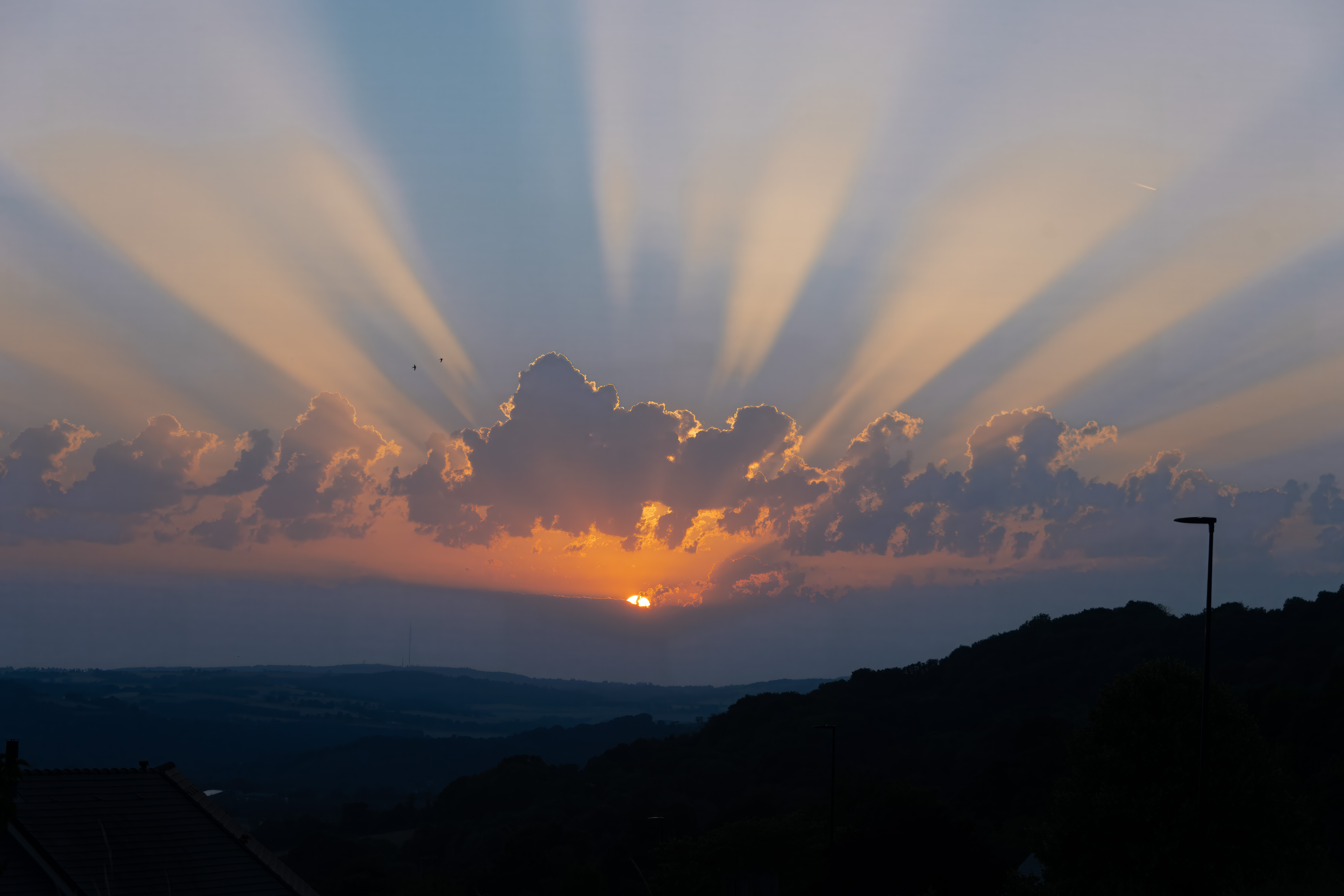 Sunset with crepuscular rays over hills HD Wallpaper