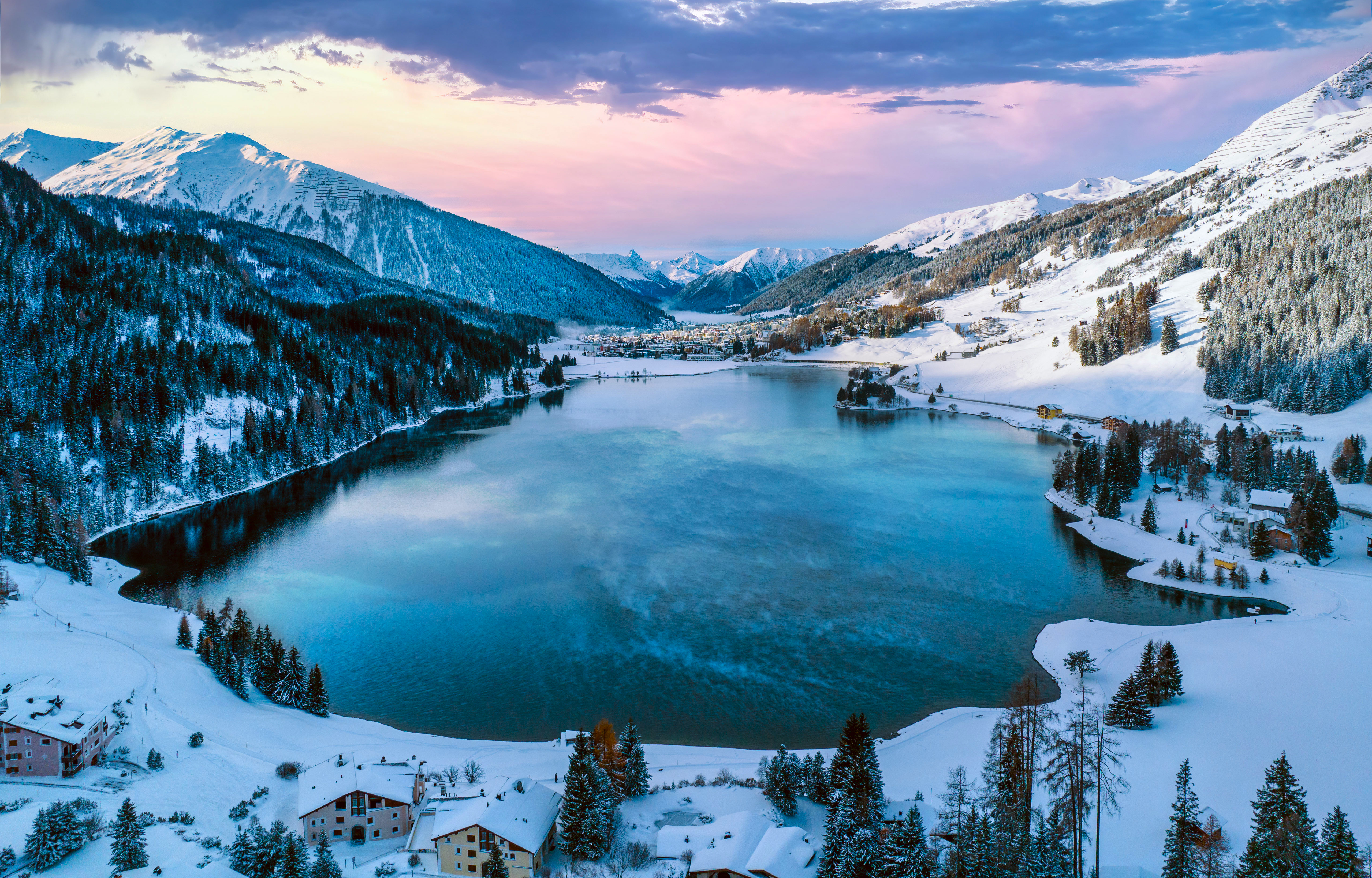 Snowy village by a lake surrounded by mountains HD Wallpaper