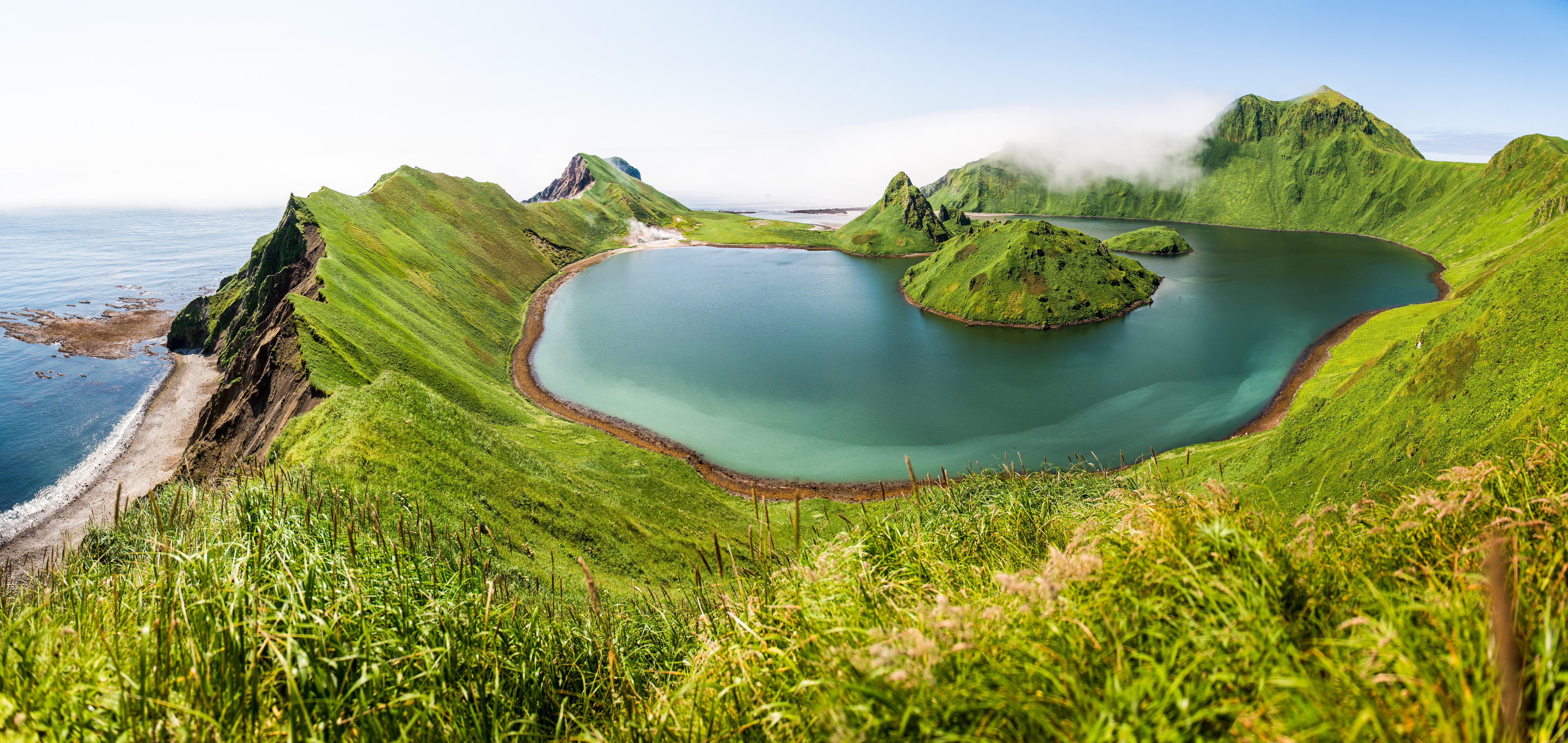 Green island with a lake and misty mountains HD Wallpaper
