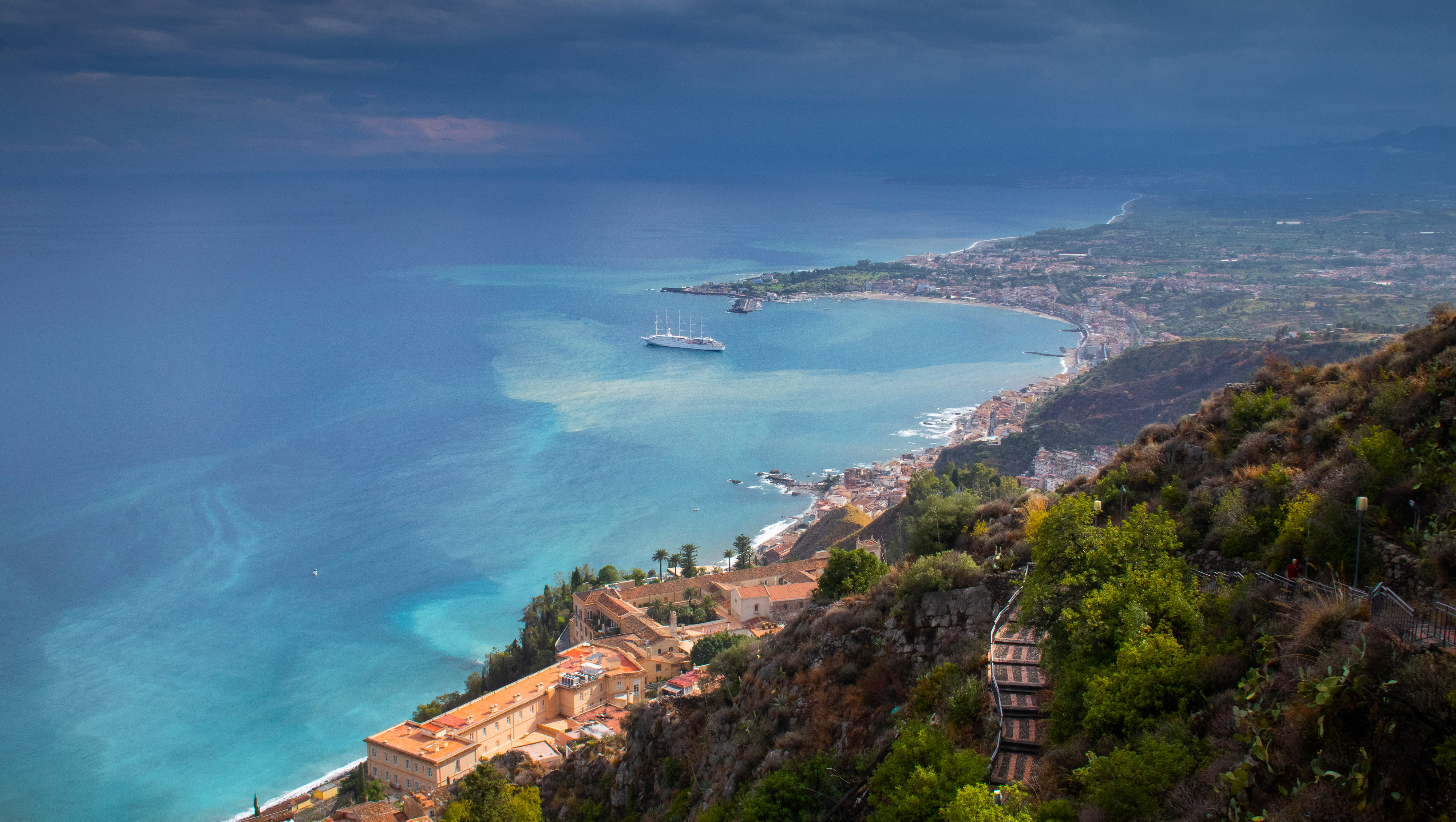 Cruise ship in a bay with a coastal town and mountains HD Wallpaper