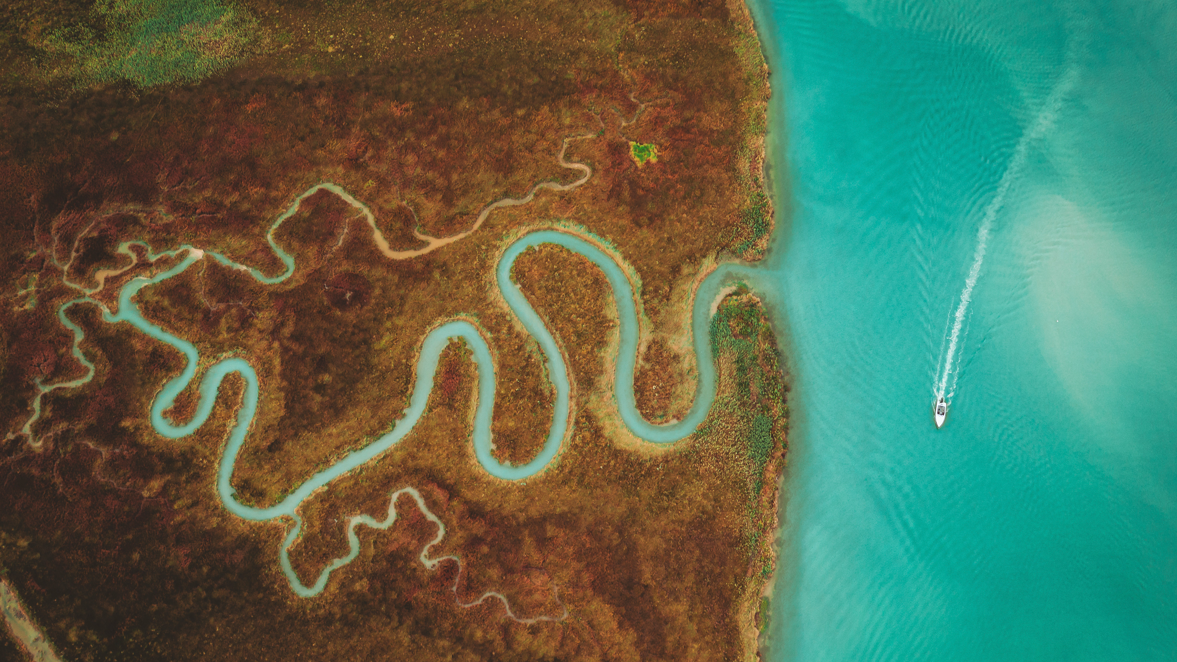 Boat navigating a winding river in a lagoon HD Wallpaper