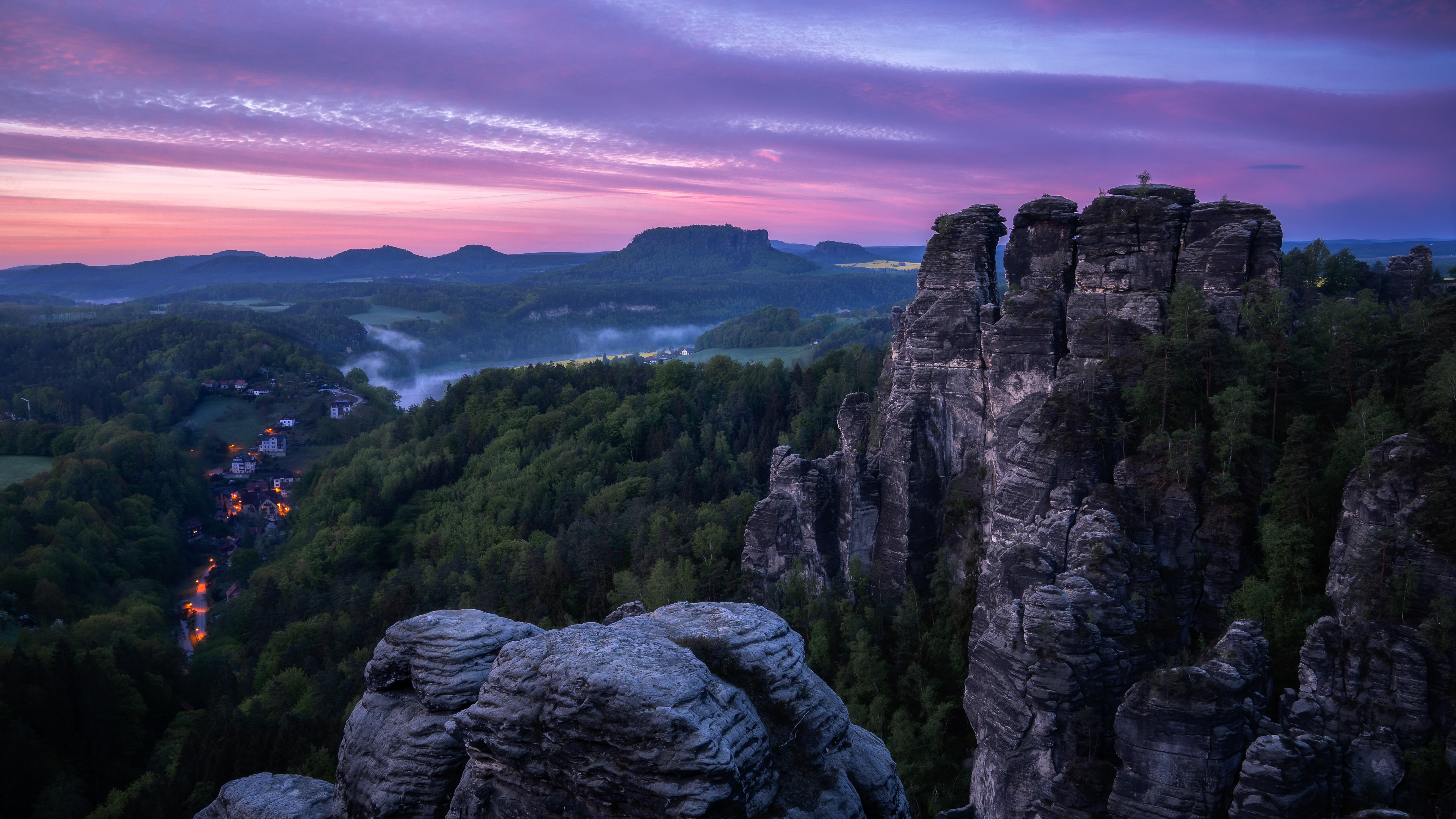 Rocky peaks and village at sunrise with purple sky HD Wallpaper