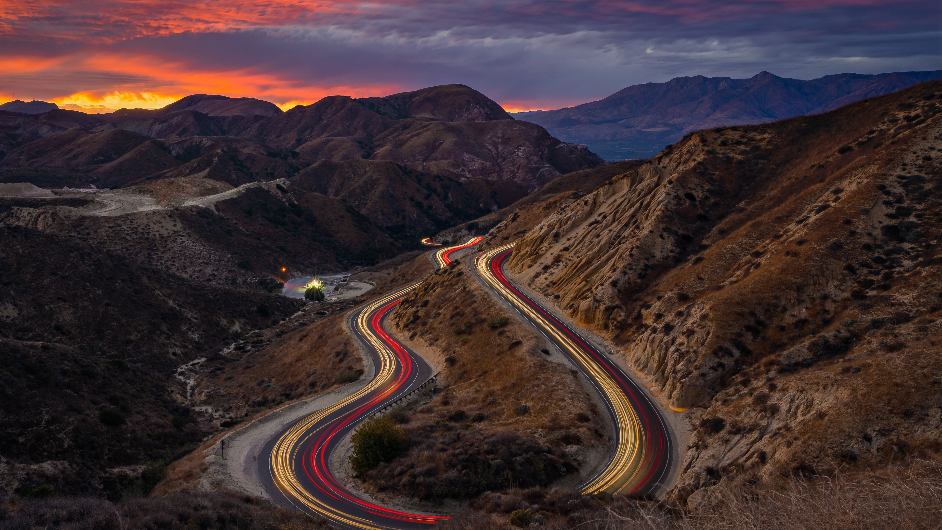 Winding mountain road at sunset with light trails HD Wallpaper