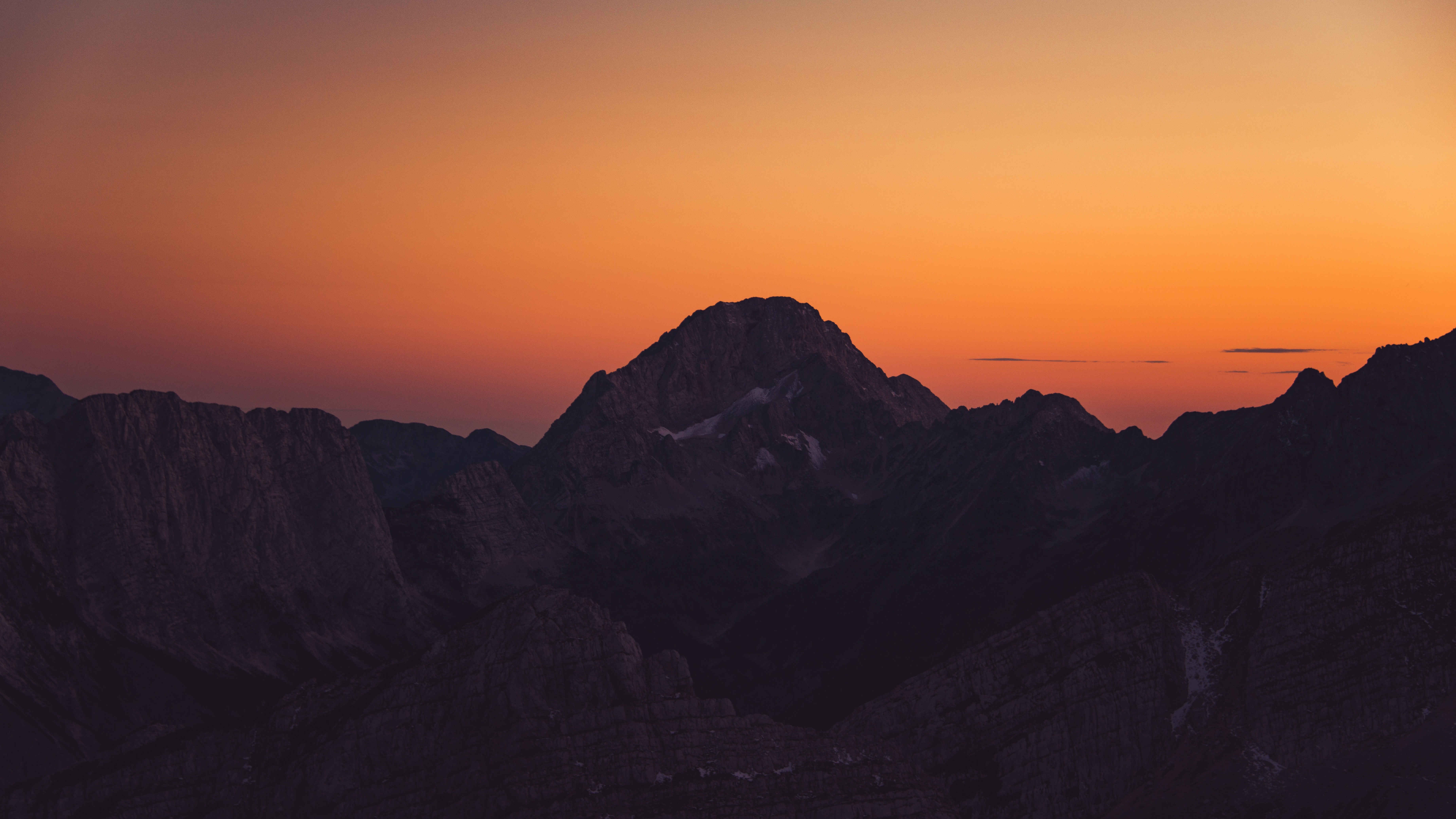 Silhouette of mountains against an orange sunset sky HD Wallpaper