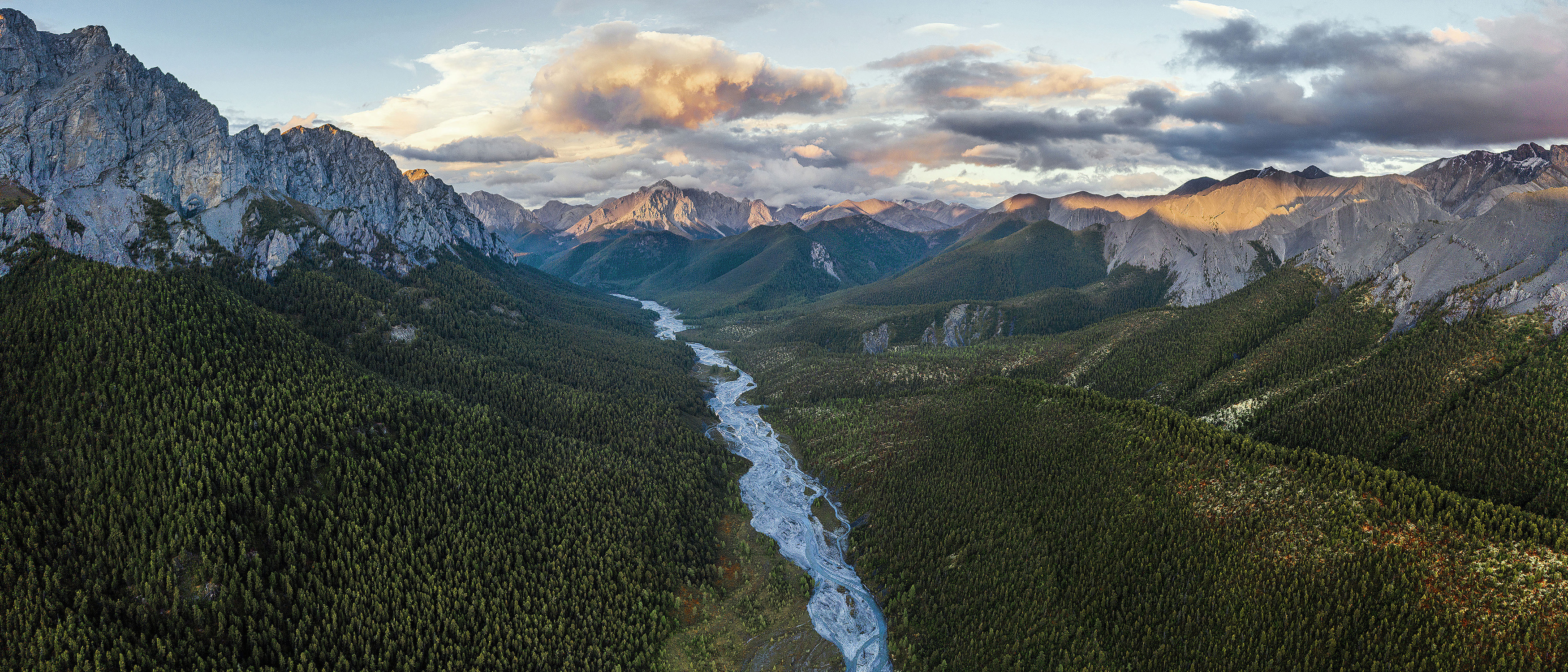 River flowing through a forested mountain valley at sunset HD Wallpaper