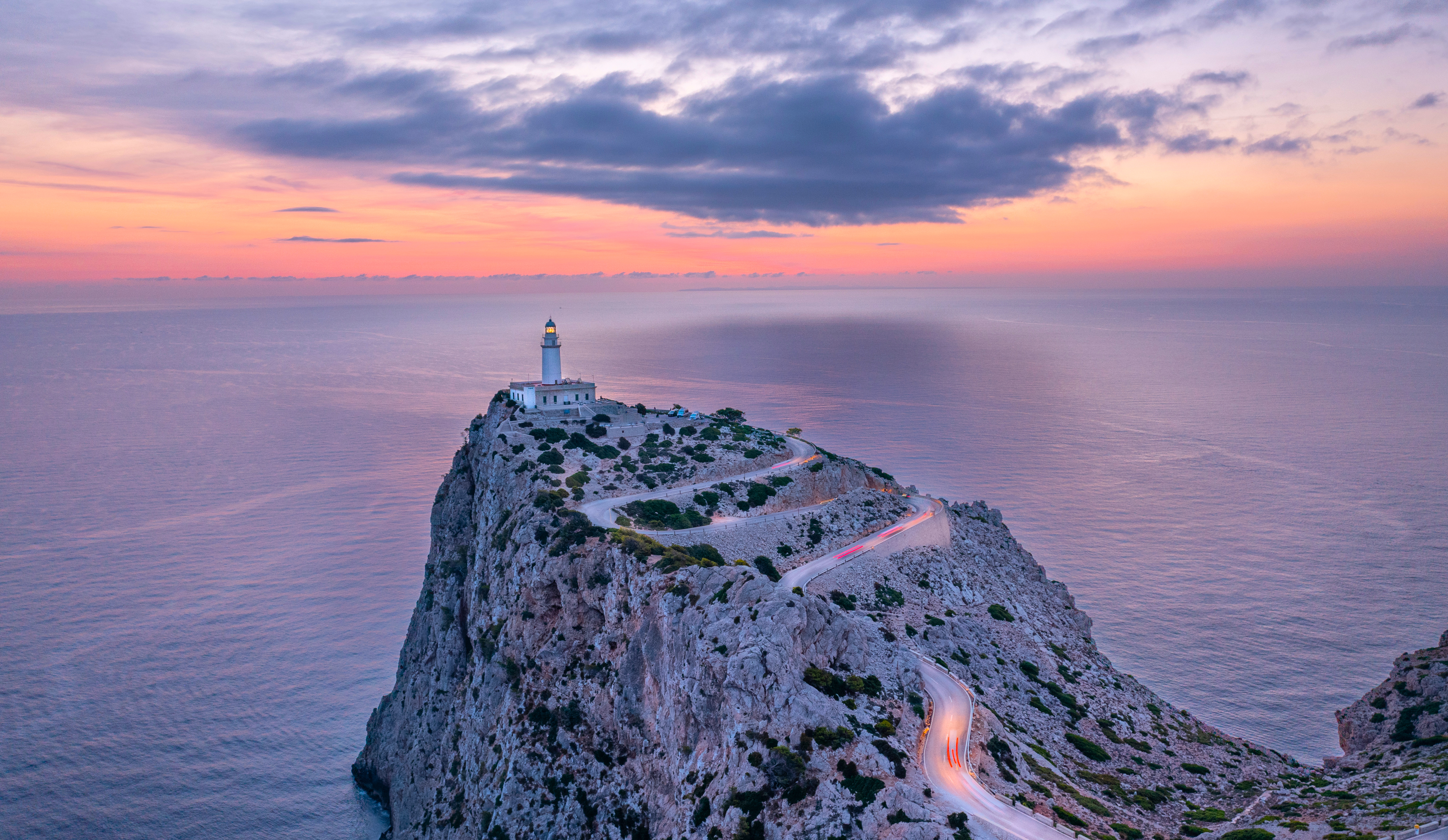 Lighthouse on a cliff overlooking the sea at sunset HD Wallpaper