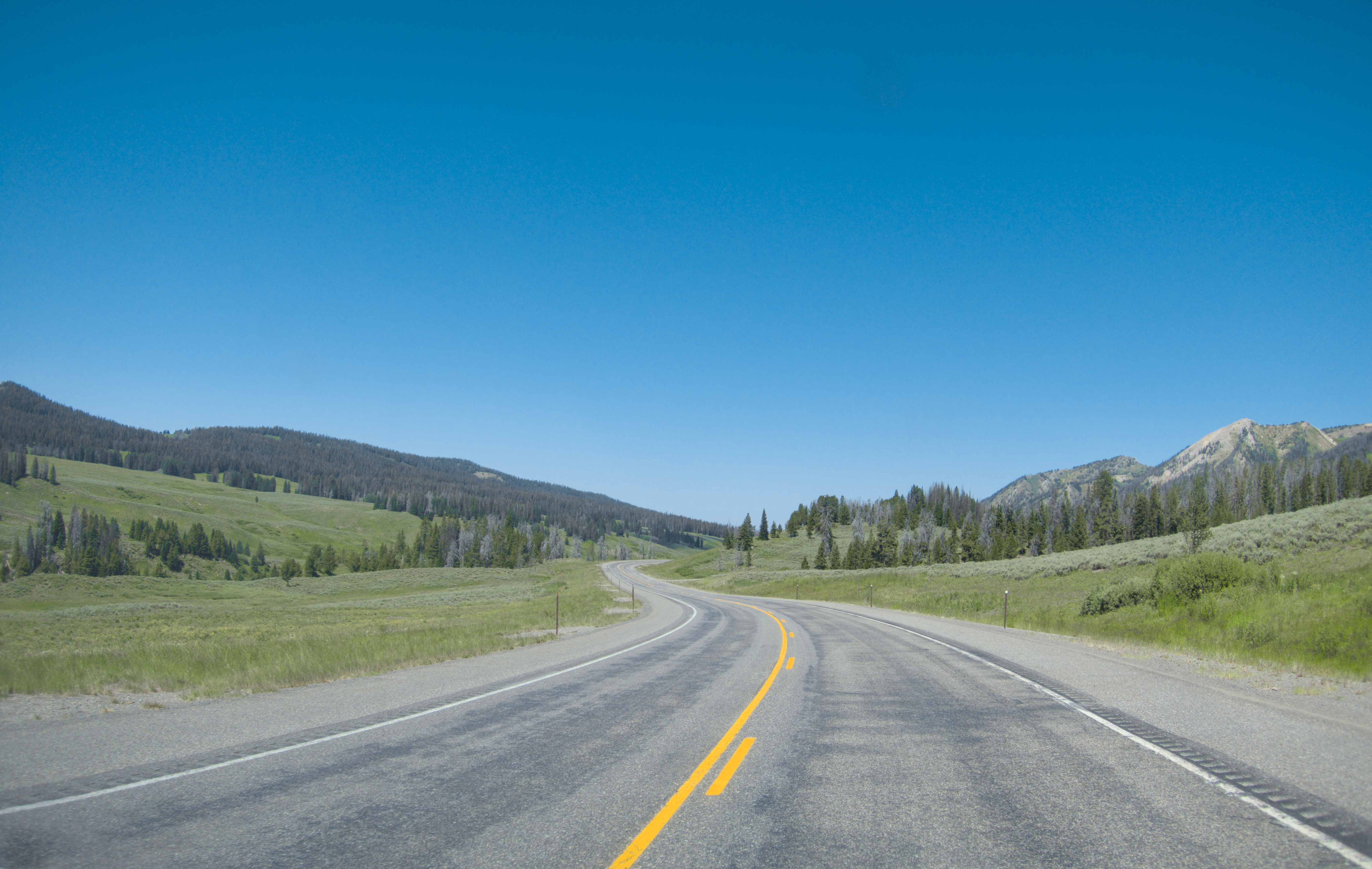 Winding Highway Through Wyoming Mountains Under Clear Blue Sky HD Wallpaper