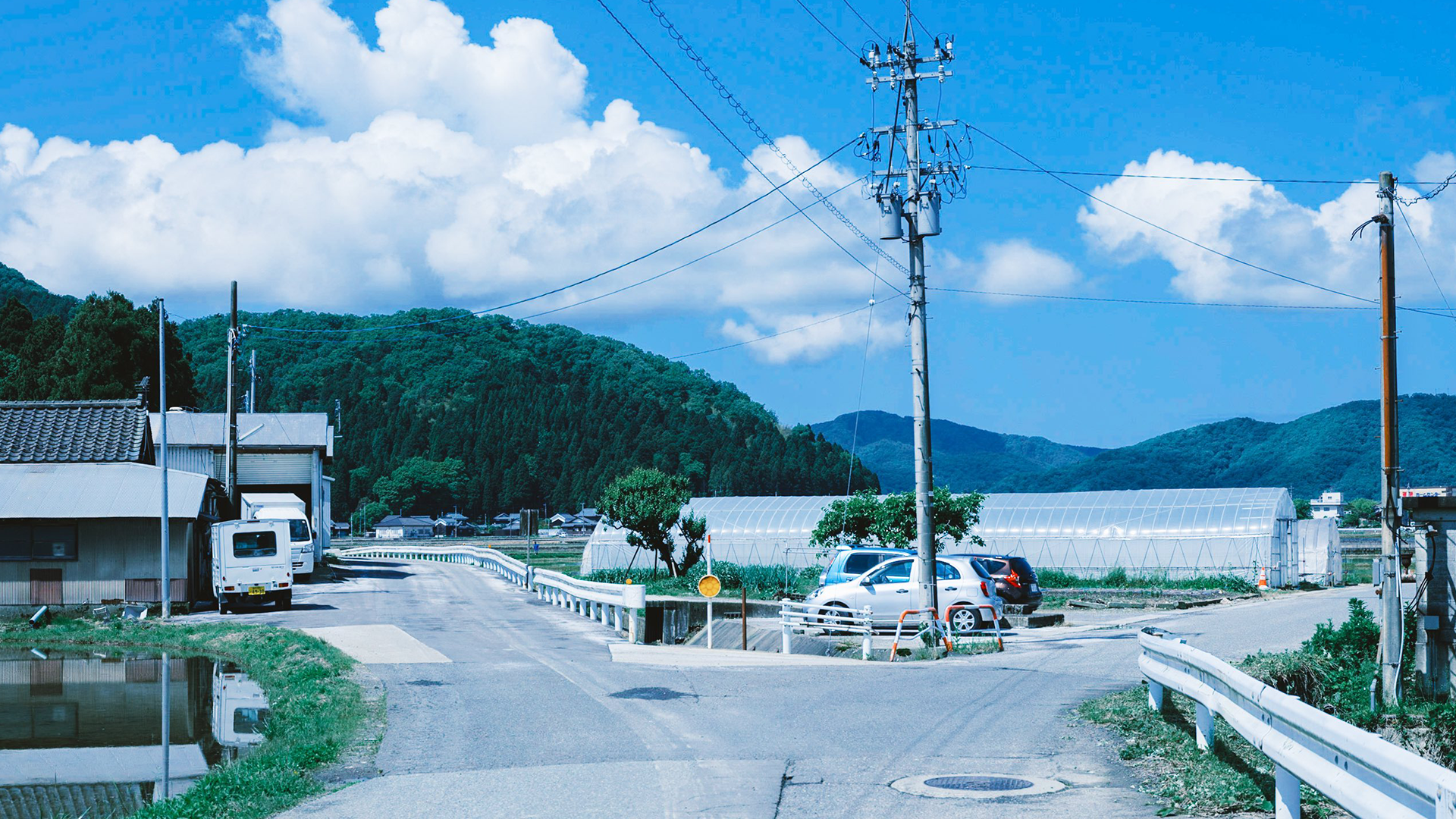 Cars parked near greenhouses on a rural road in Japan HD Wallpaper