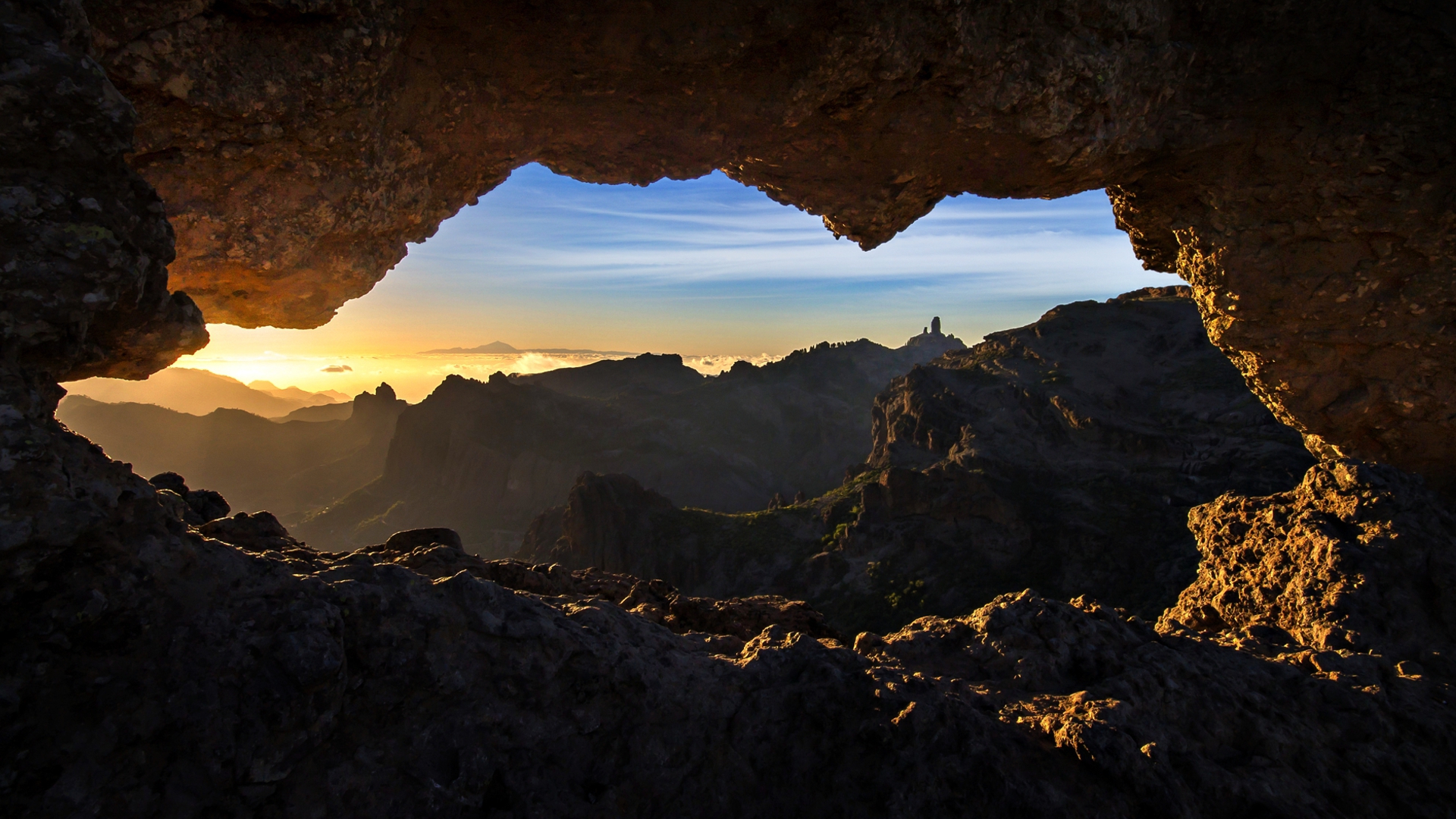 Cave opening framing sunset over Gran Canaria mountains HD Wallpaper