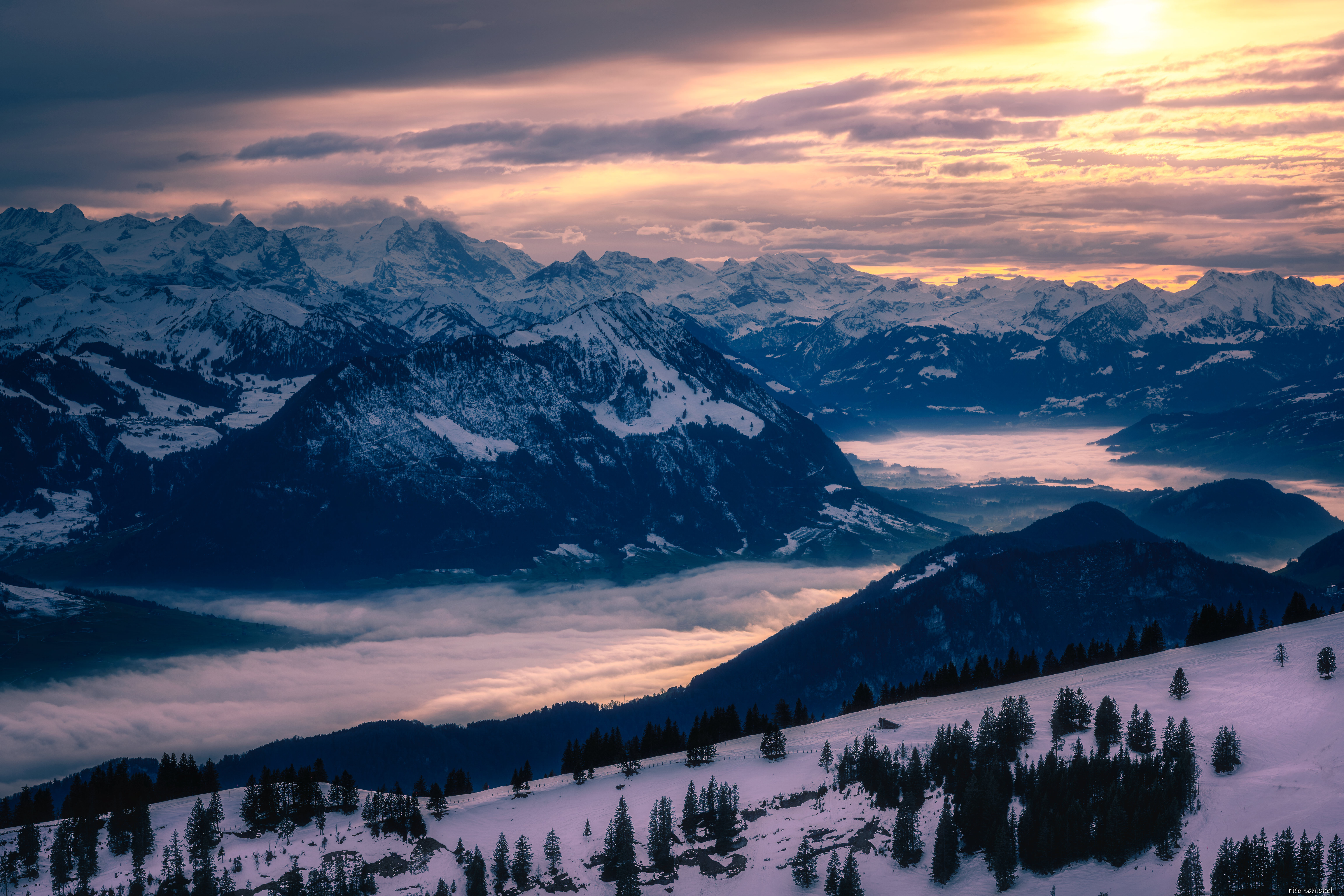 Snowy mountains at sunset with mist in the valleys HD Wallpaper