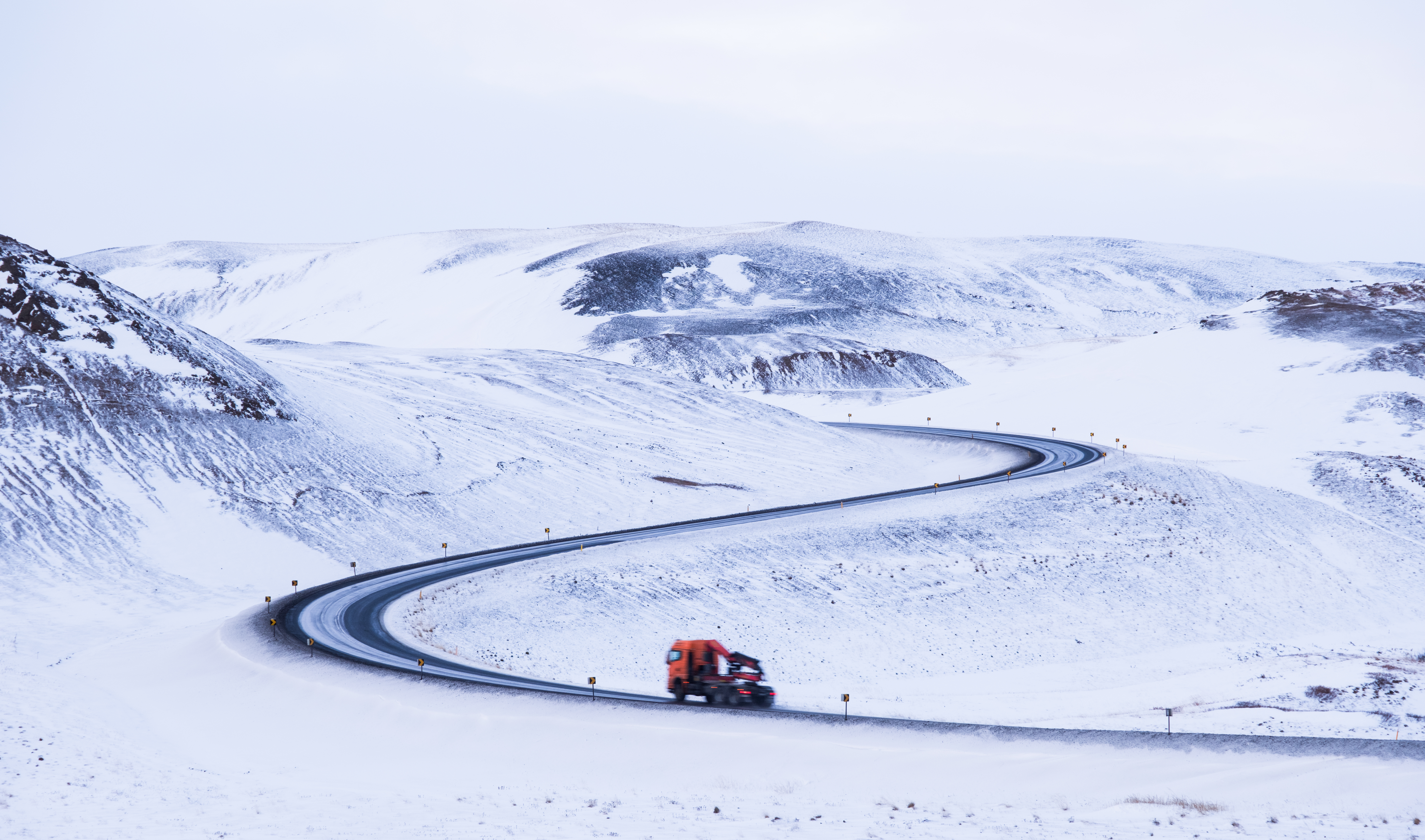 Driving on a winding snowy road in Iceland HD Wallpaper