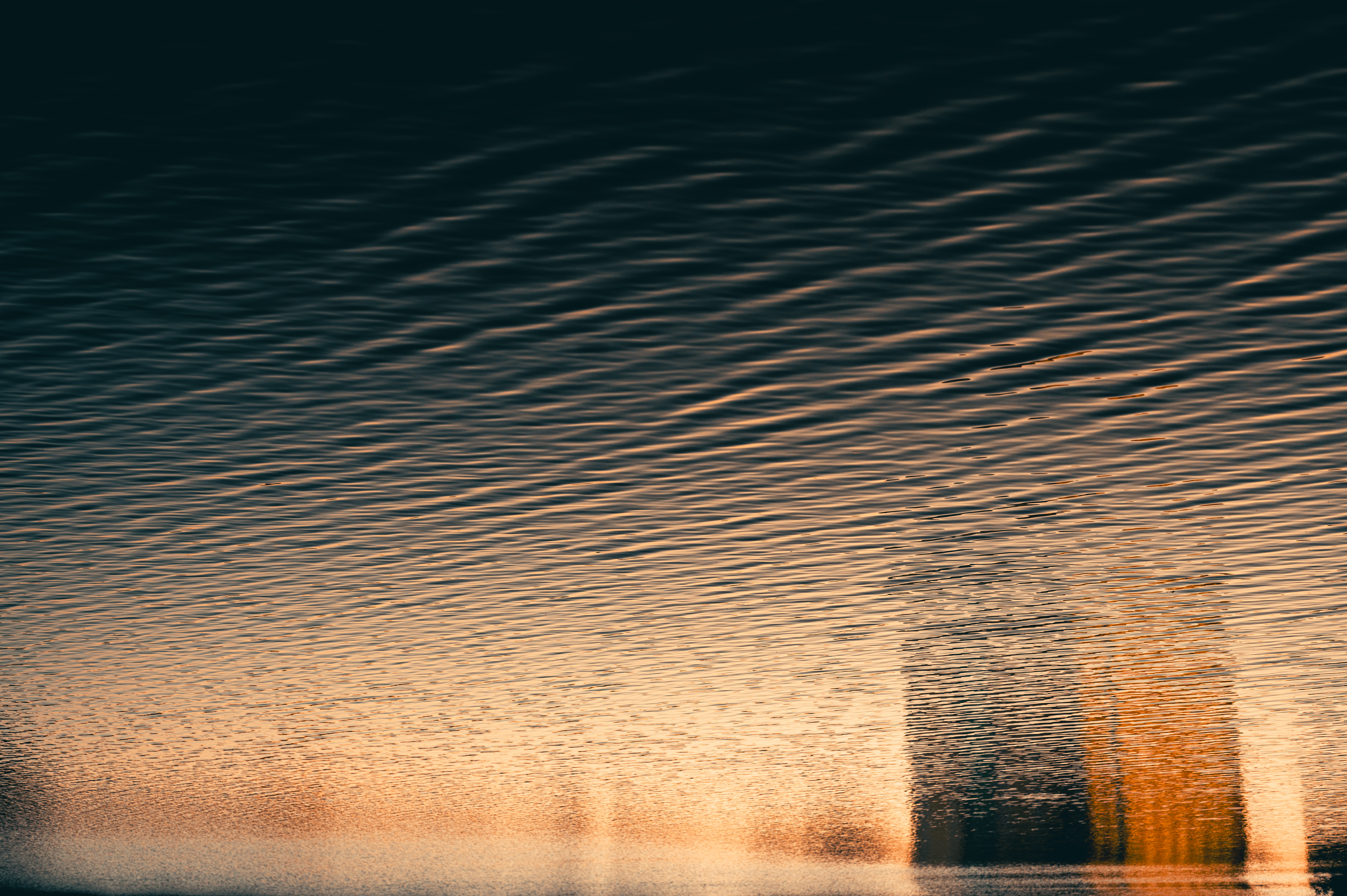 Reflection of buildings on rippling water at sunset HD Wallpaper