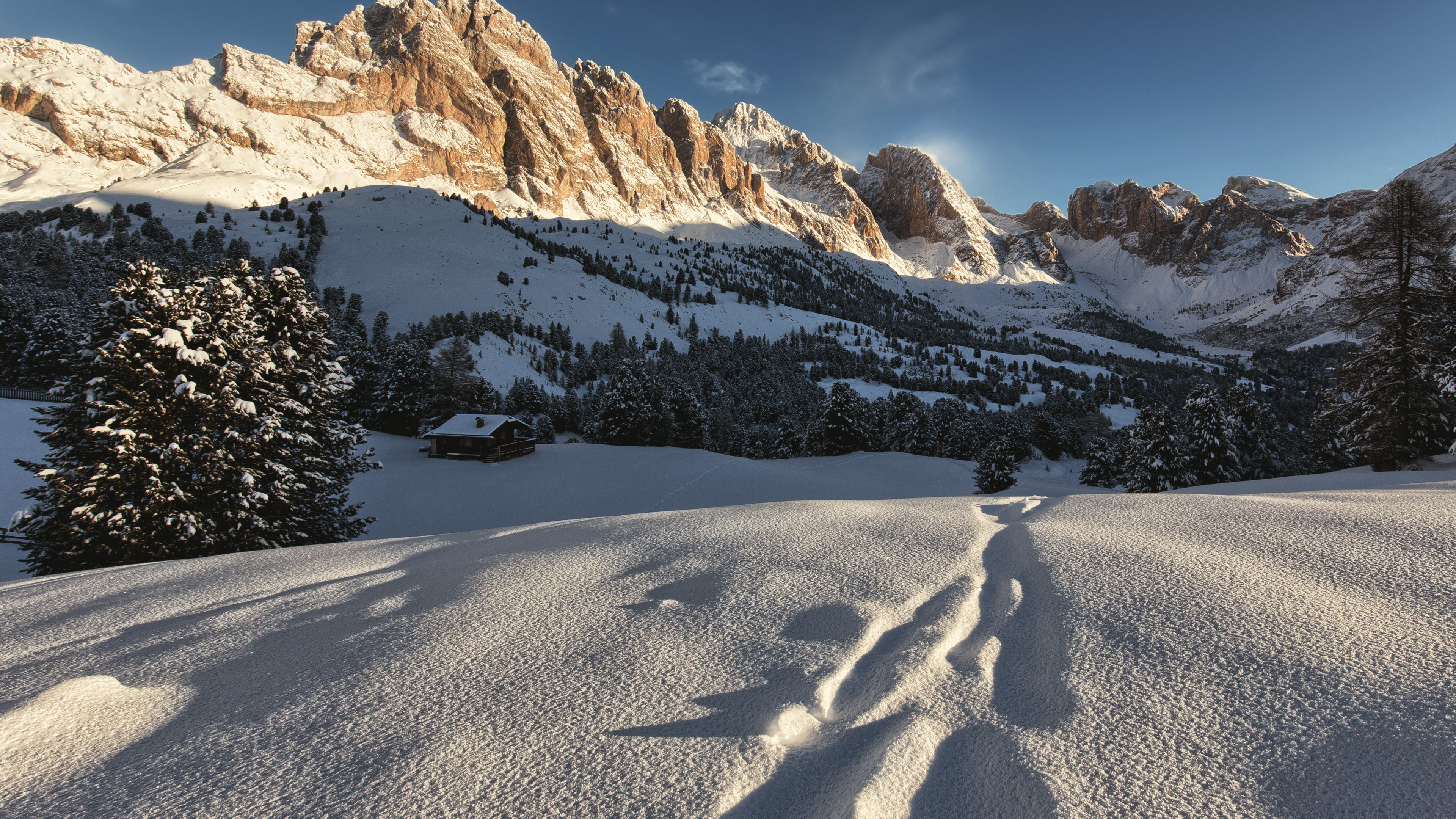 Snowy mountain peaks at sunset with footprints in the snow HD Wallpaper