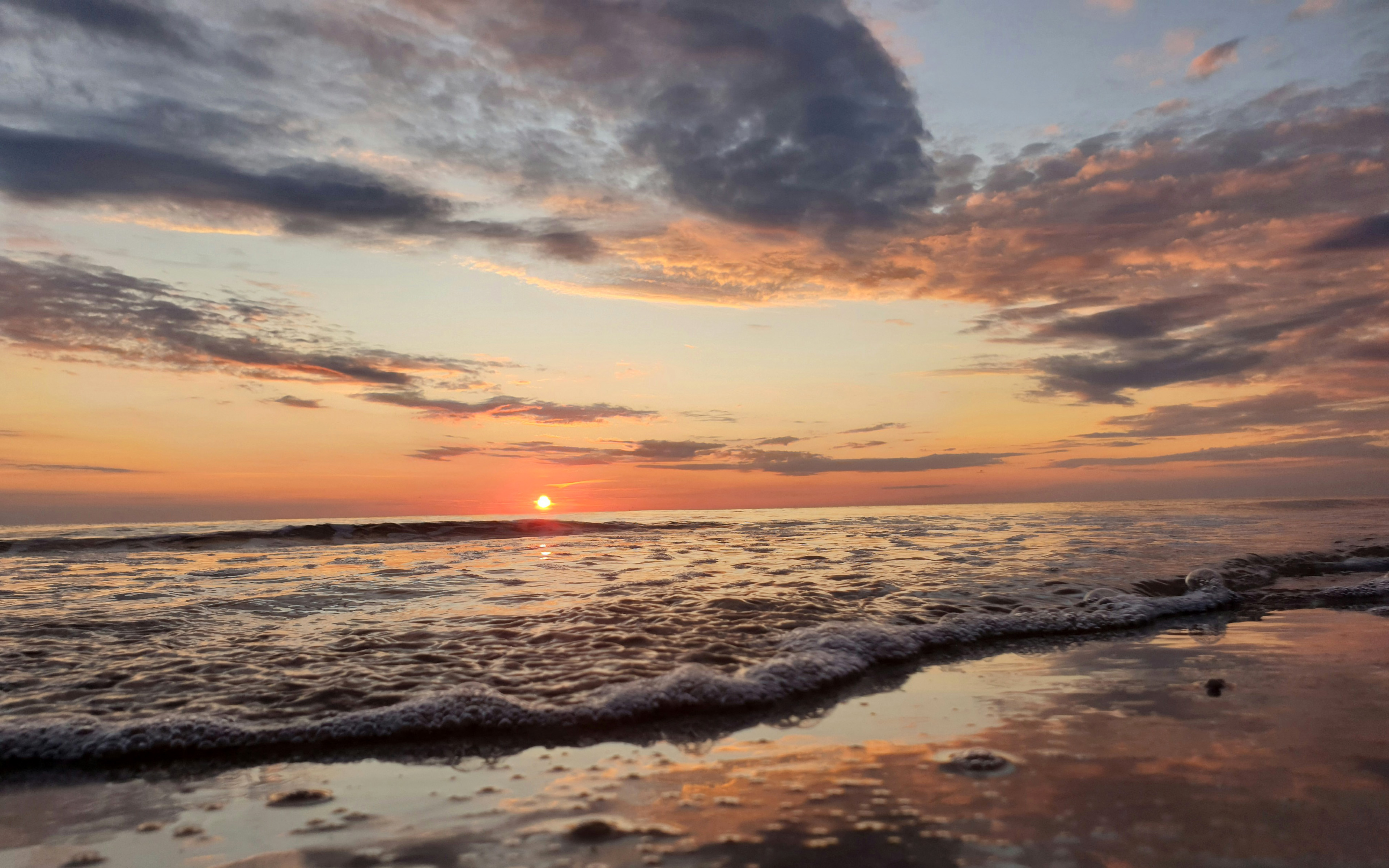 Sunset over the sea with gentle waves on the beach HD Wallpaper