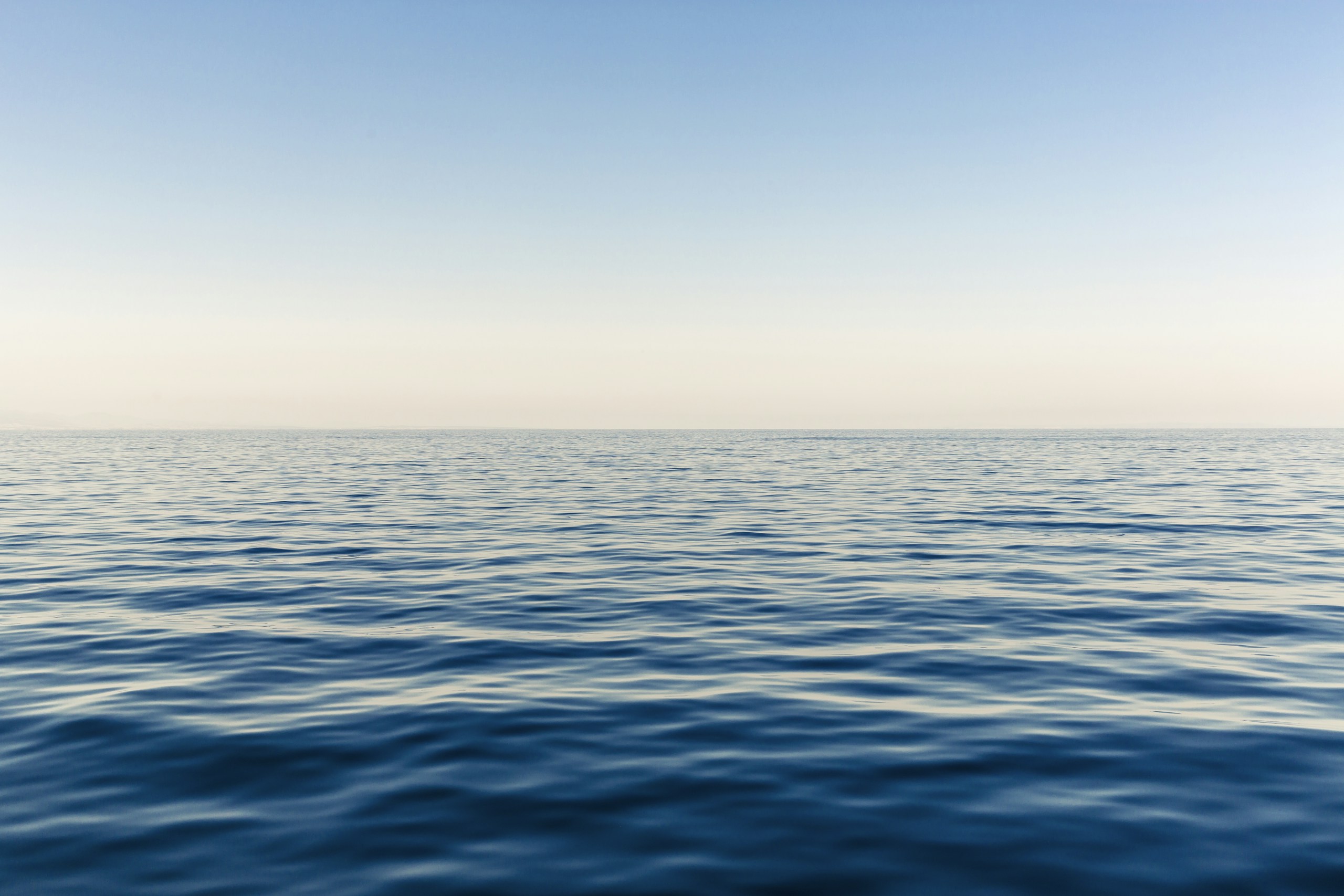 Calm blue ocean water under a clear sky HD Wallpaper